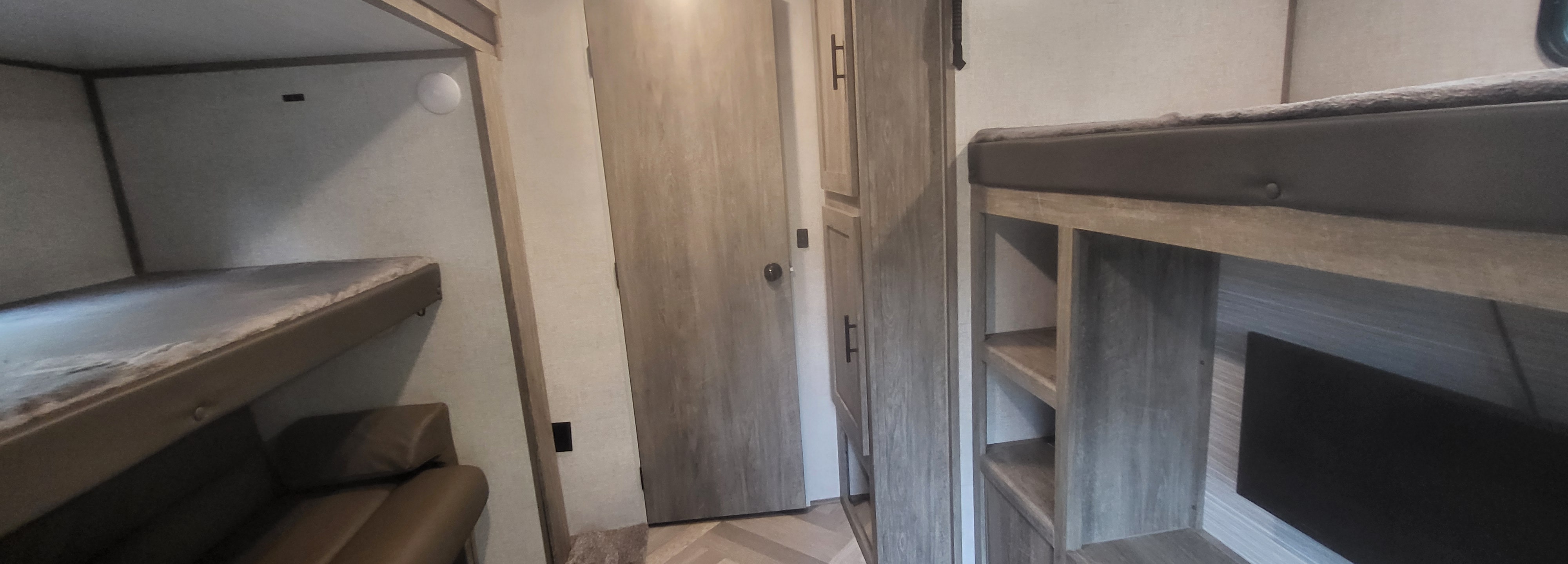 Modern rv rental cabin interior: twin bunk beds, a cozy couch, a closed door, and shelving with an integrated TV.. Forest River Salem Hemisphere 2021