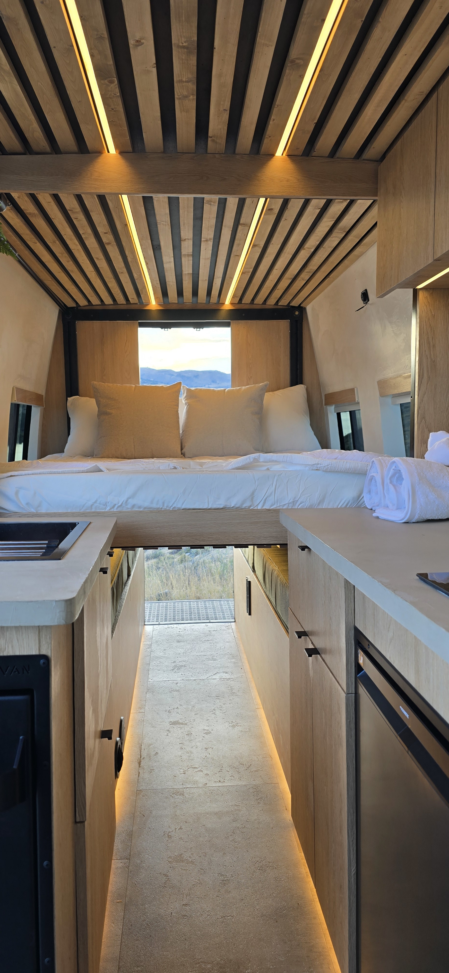 Stylish rv rental for van life: elevated bed, mountain views, slatted wood ceiling lighting, & modern compact kitchen.. Mercedes Mercedes Sprinter Adventure Van 2025