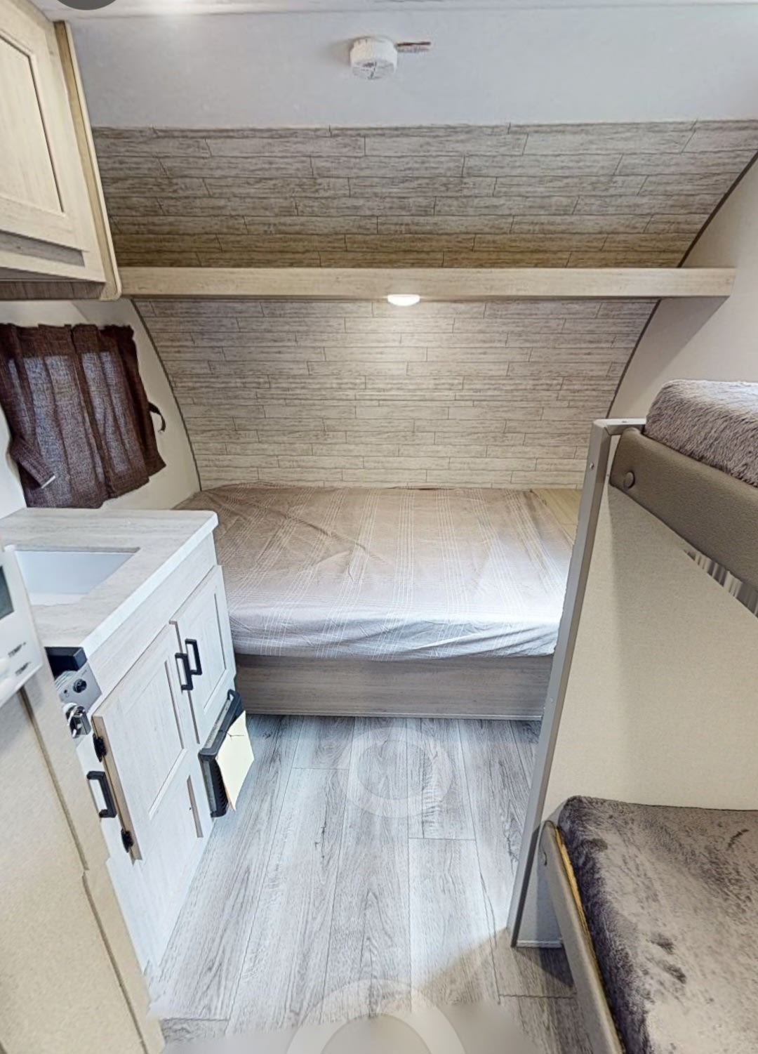 RV rental interior: bright bedroom features a bed, partial bunk bed, and sink area. Light wood tones & flooring.. Forest River Coachmen Catalina Summit 2025