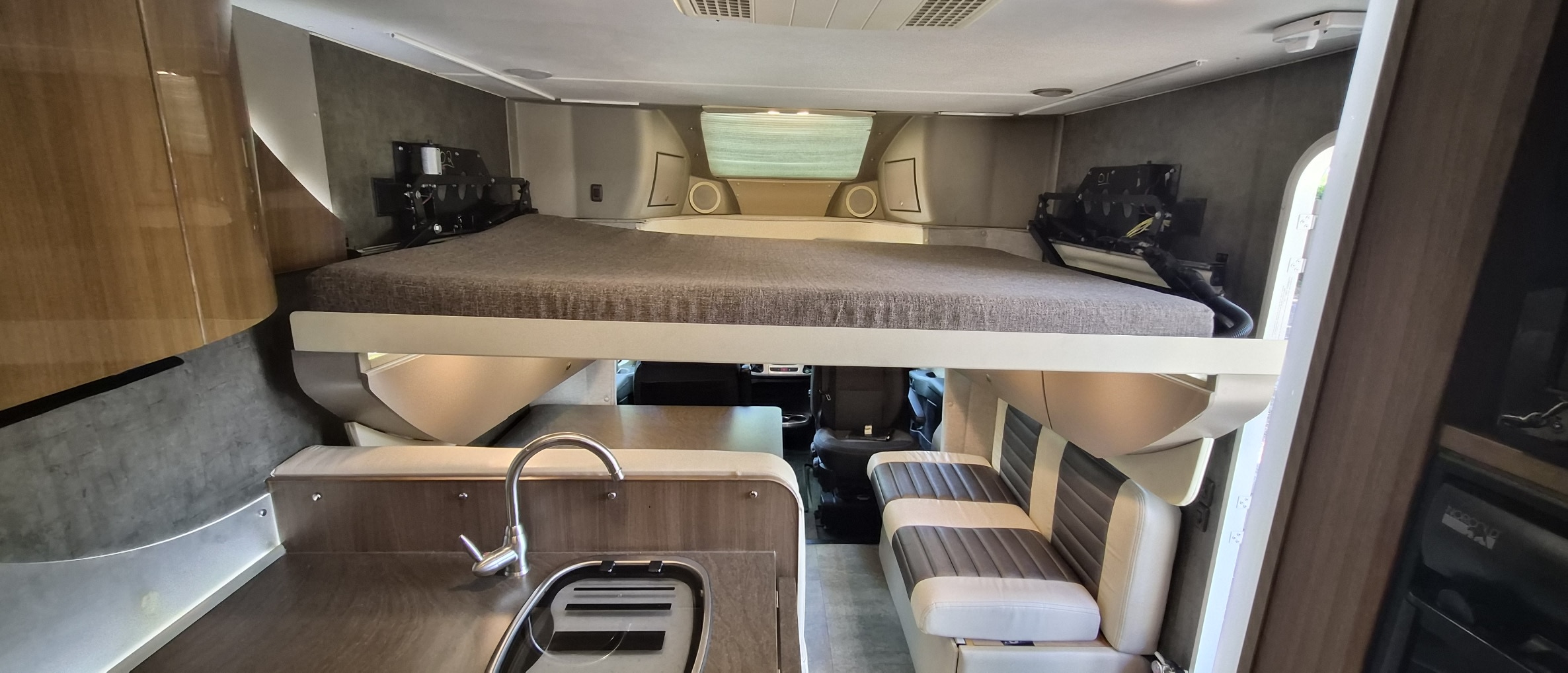 Modern RV rental interior: overhead bed, kitchen with sink, and comfortable dinette seating for your next adventure.. Winnebago Trend 2015