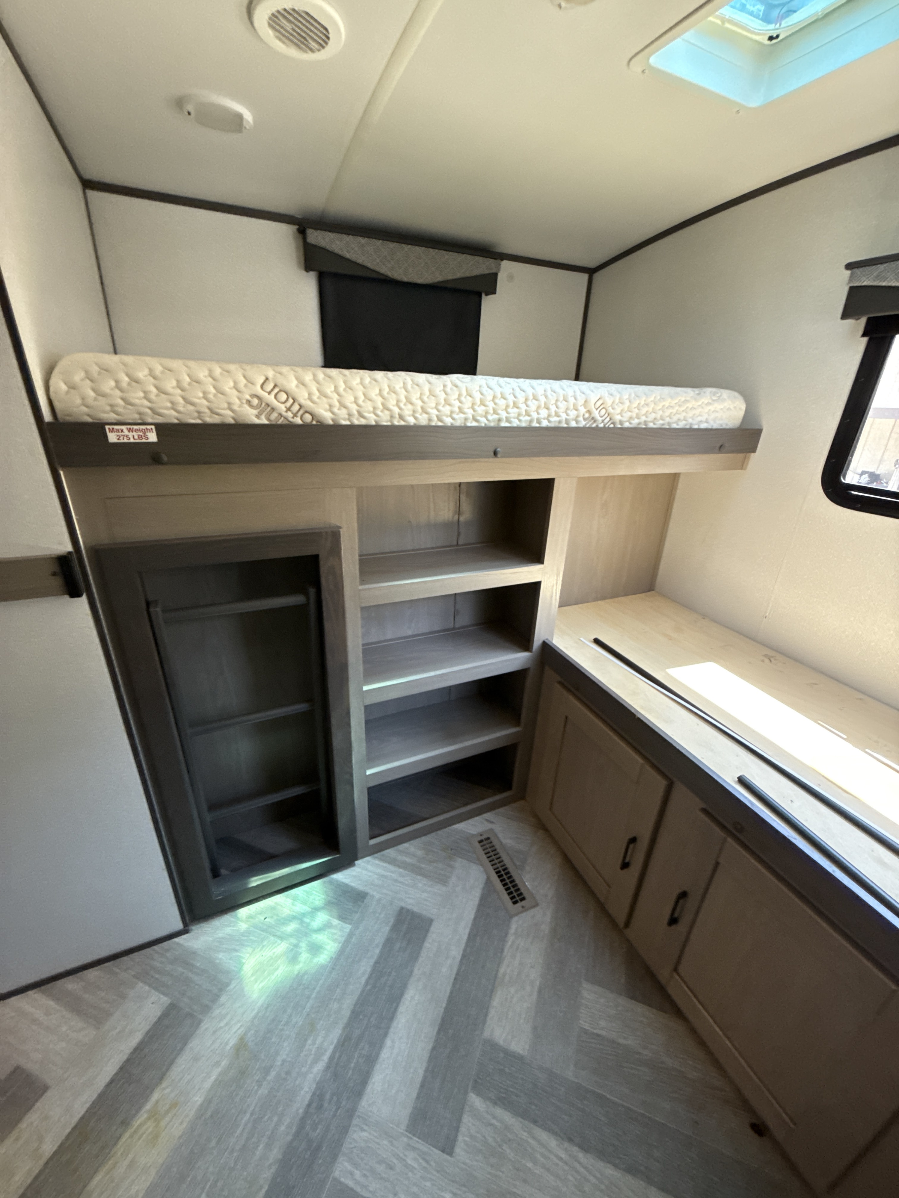 Modern RV rental interior: bunk bed with 275lb limit, shelving, and cabinets over stylish herringbone flooring.. Twilight RVS Signature 2021