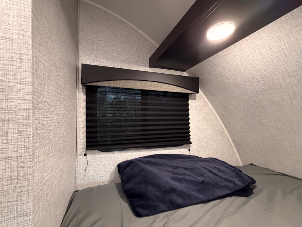 RV rental interior: a cozy bunk bed nook with textured walls, a closed window blind, and an overhead light.. Braxton Creek Bushwhacker Plus 2022