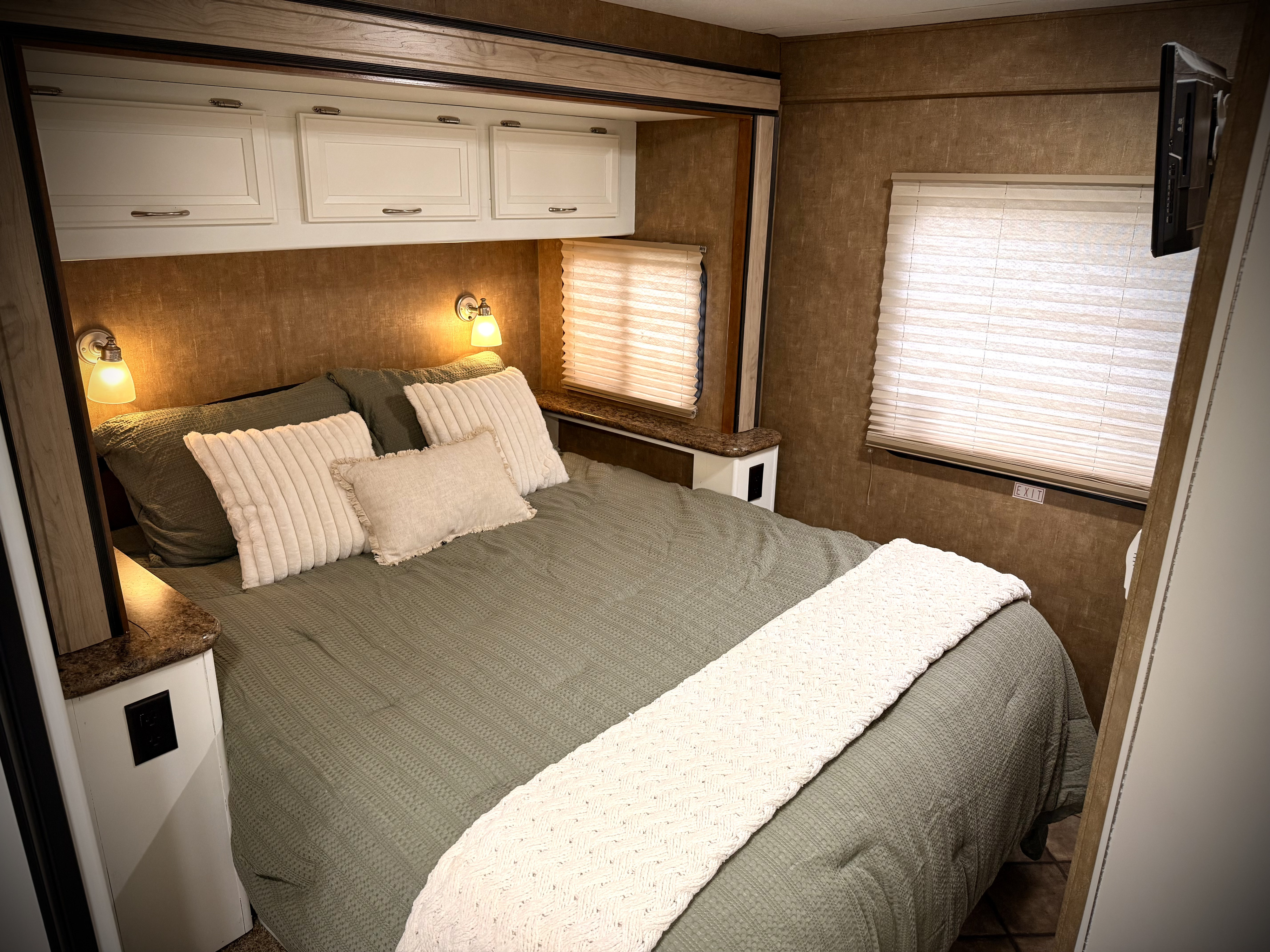 Comfortable RV rental bedroom with cozy bed, overhead cabinets, and ambient lighting for a relaxing journey.. Thor Four Winds 2014
