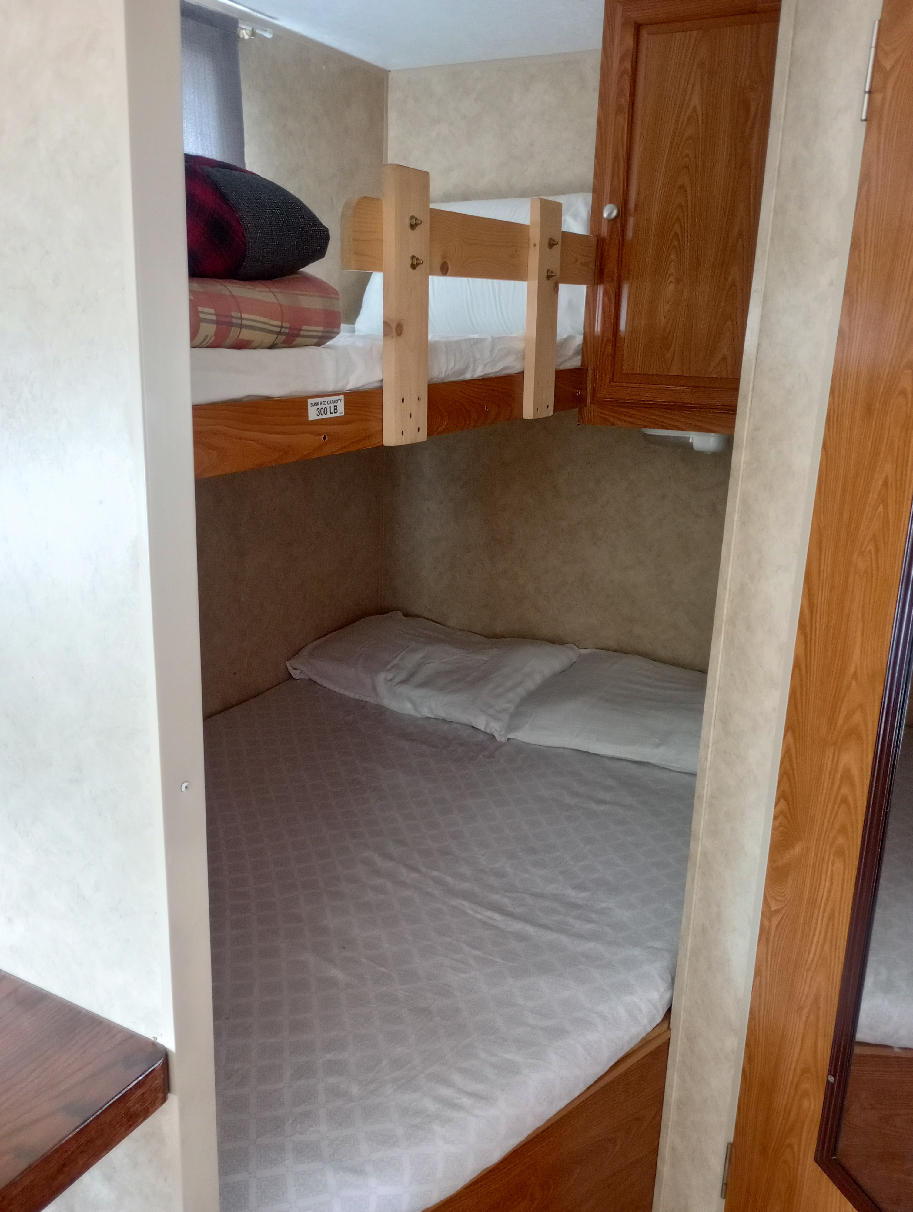 RV rental interior: cozy bunk beds with pillows, blankets. Top bunk clearly marked for 300 lb capacity.. Dutchmen Dutchmen Trailer 2008