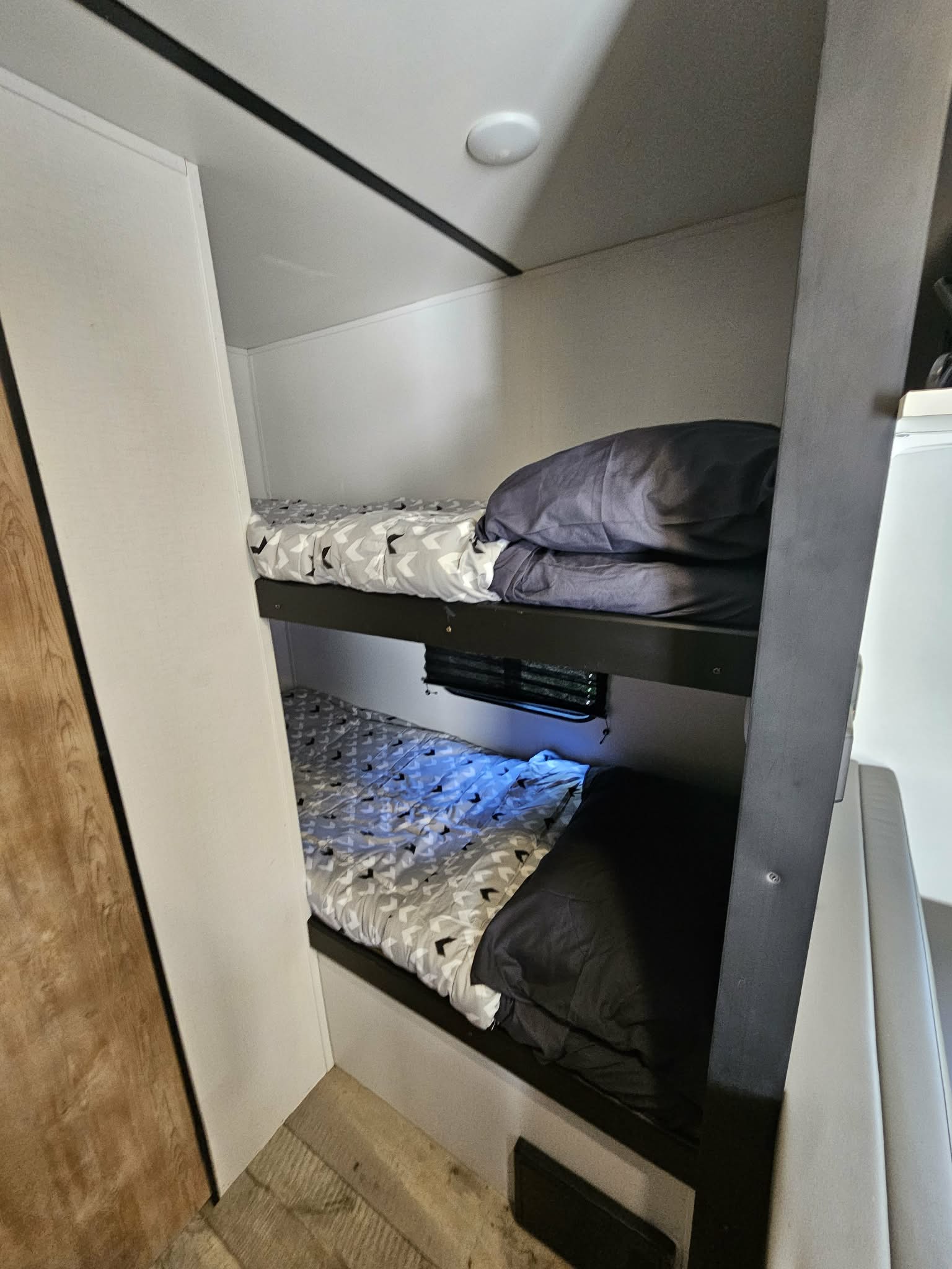 Bunk beds in an rv rental, featuring neat geometric bedding and dark pillows, provide a functional sleeping area.. Keystone RV Springdale 2022