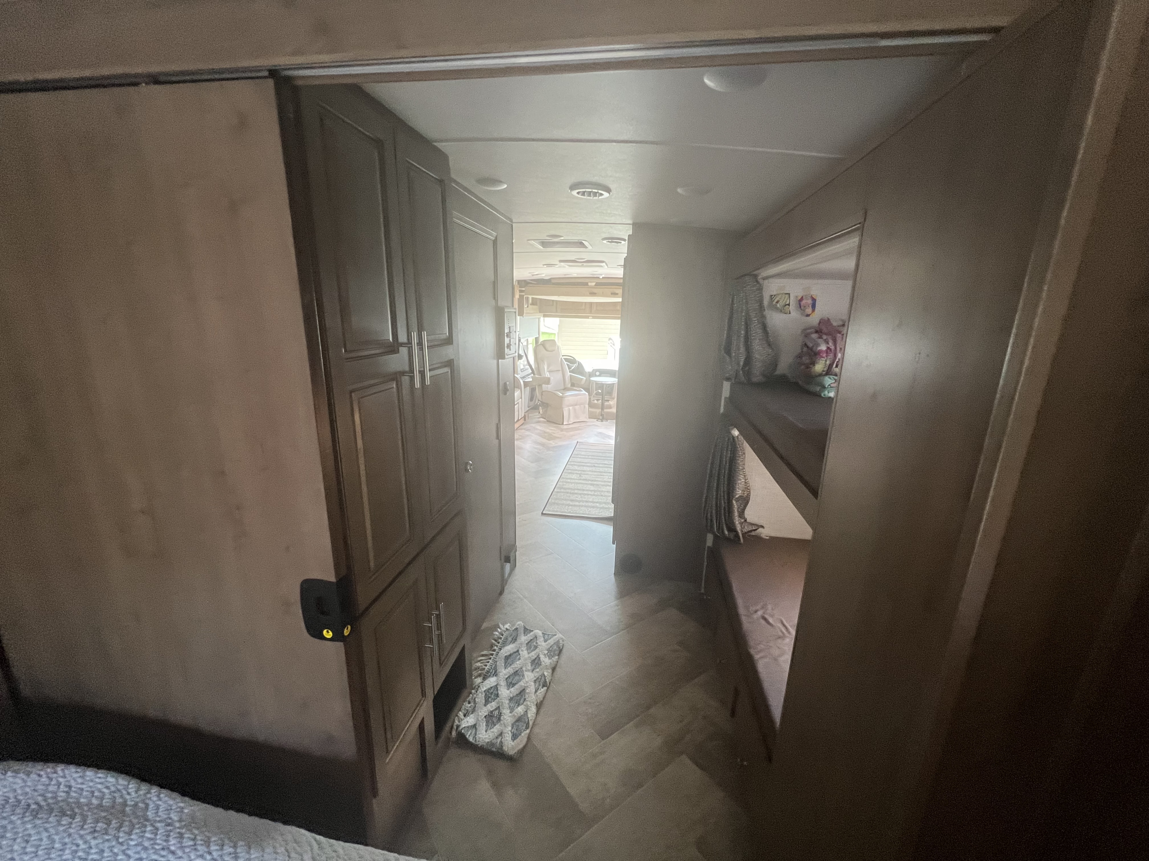 RV rental interior: a hallway leading to a living area, featuring dark cabinets, bunk beds, & a peek-a-boo cat near the bed.. Georgetown GT3 2020