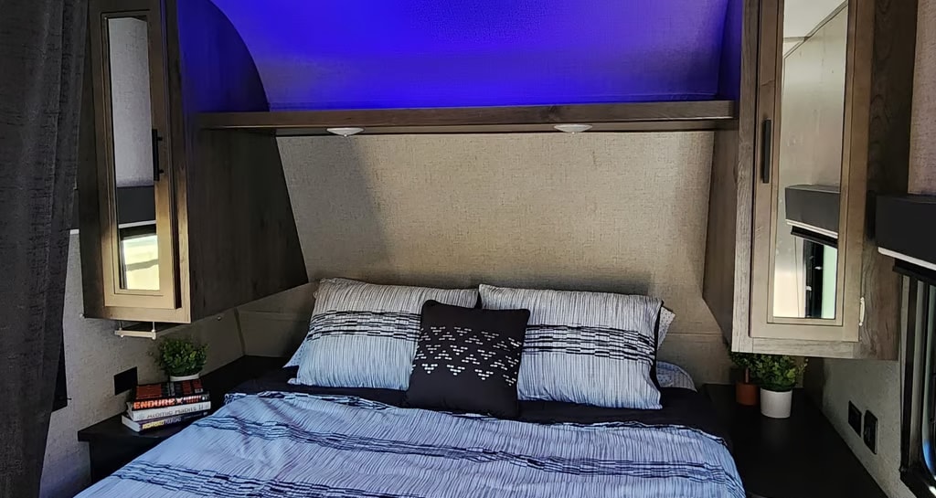 Cozy rv rental bedroom featuring a comfortable bed, blue ambient lighting, mirrored storage cabinets, and a padded headboard.. Jayco Jay Flight SLX Rocky Mountain Edition 2020