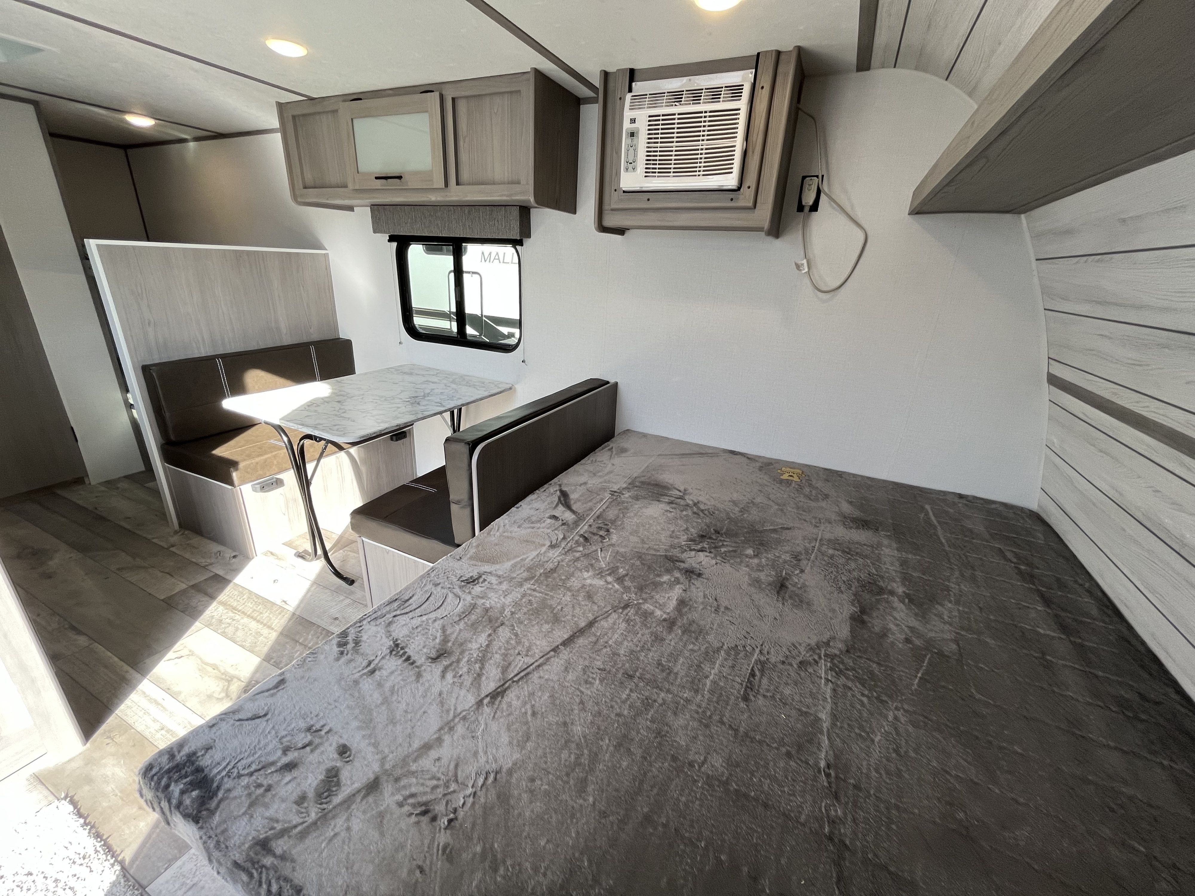 RV rental interior: A compact living space featuring a bed, dinette area, overhead cabinets, and wall-mounted AC.. Dutchmen Coleman 2024