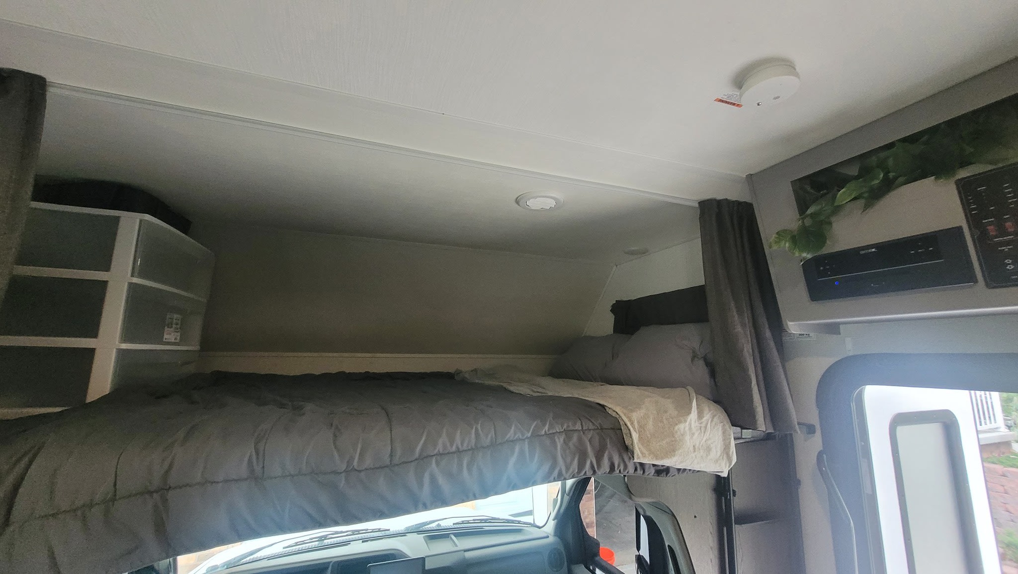 This RV rental's overhead bunk bed area features a made bed, storage unit, entertainment system, and ceiling lights.. Solera Solera Motorhome 2022