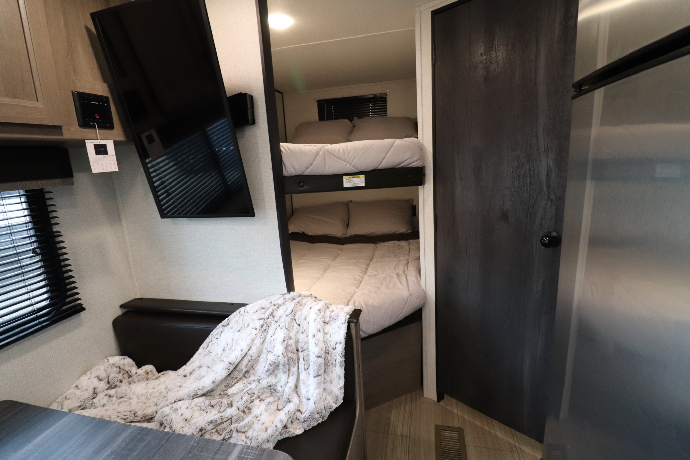 Experience comfort in this RV rental: bunk beds, a wall-mounted TV, and a cozy dinette with a soft blanket.. Keystone RV Hideout 2021