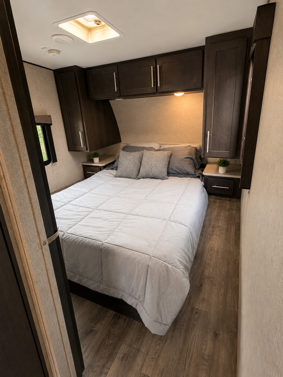 Cozy RV rental bedroom with a comfortable bed, dark wood cabinets, and roof vent.. Keystone Carbon 2018