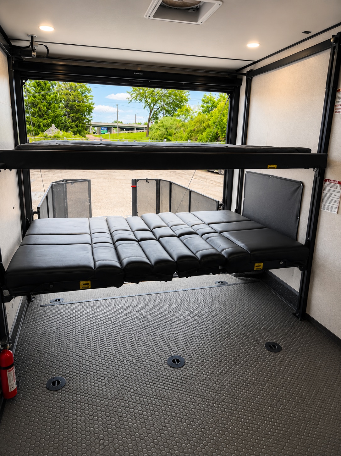 RV rental interior showing versatile bunk beds, a textured floor, and an open rear door view.. Keystone Carbon 2018