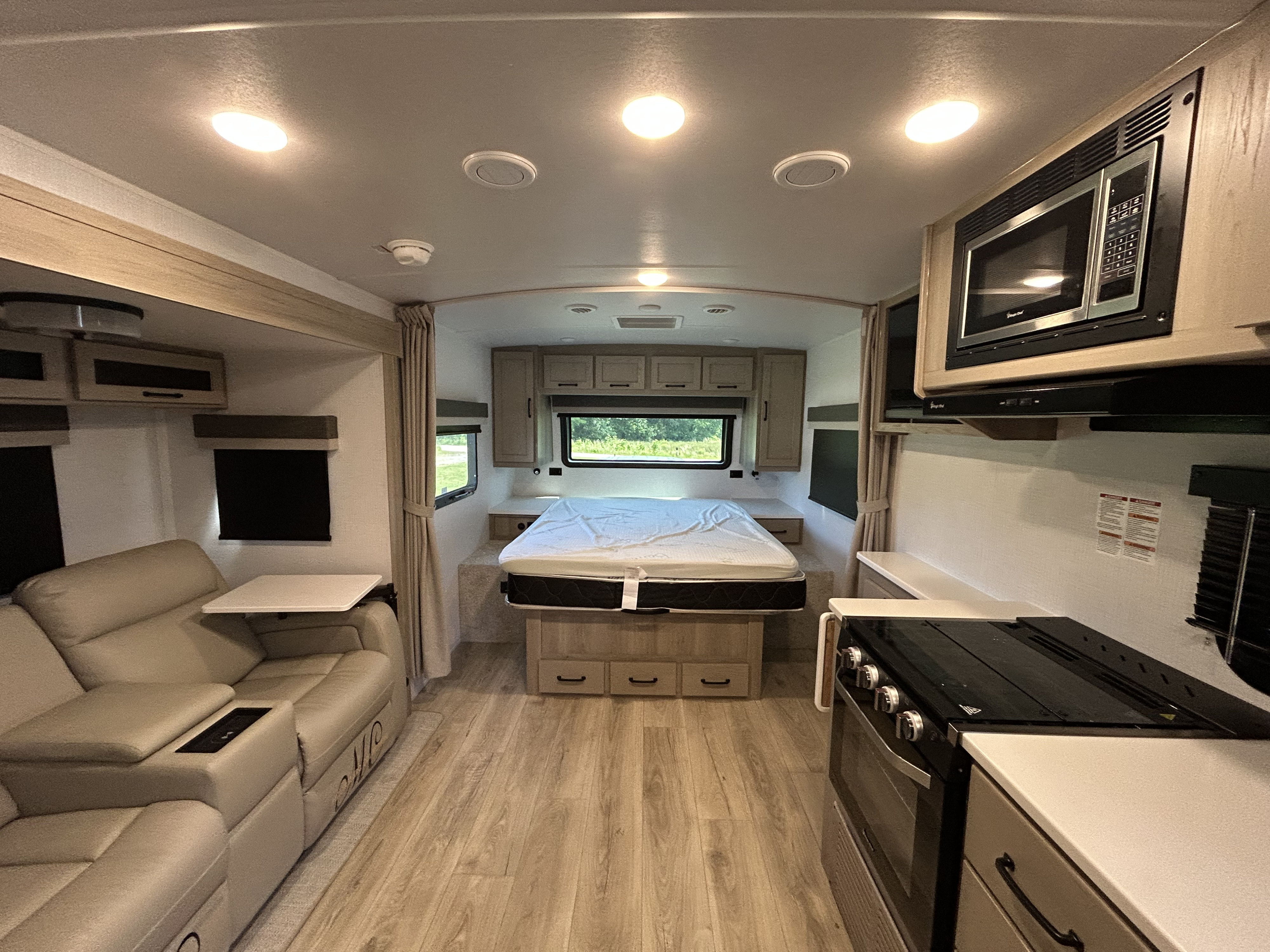 Modern RV rental interior with comfy recliners, a full kitchen, and a queen bed. Light wood cabinets & flooring create a bright space.. Forest River Rockwood Mini Lite 2025