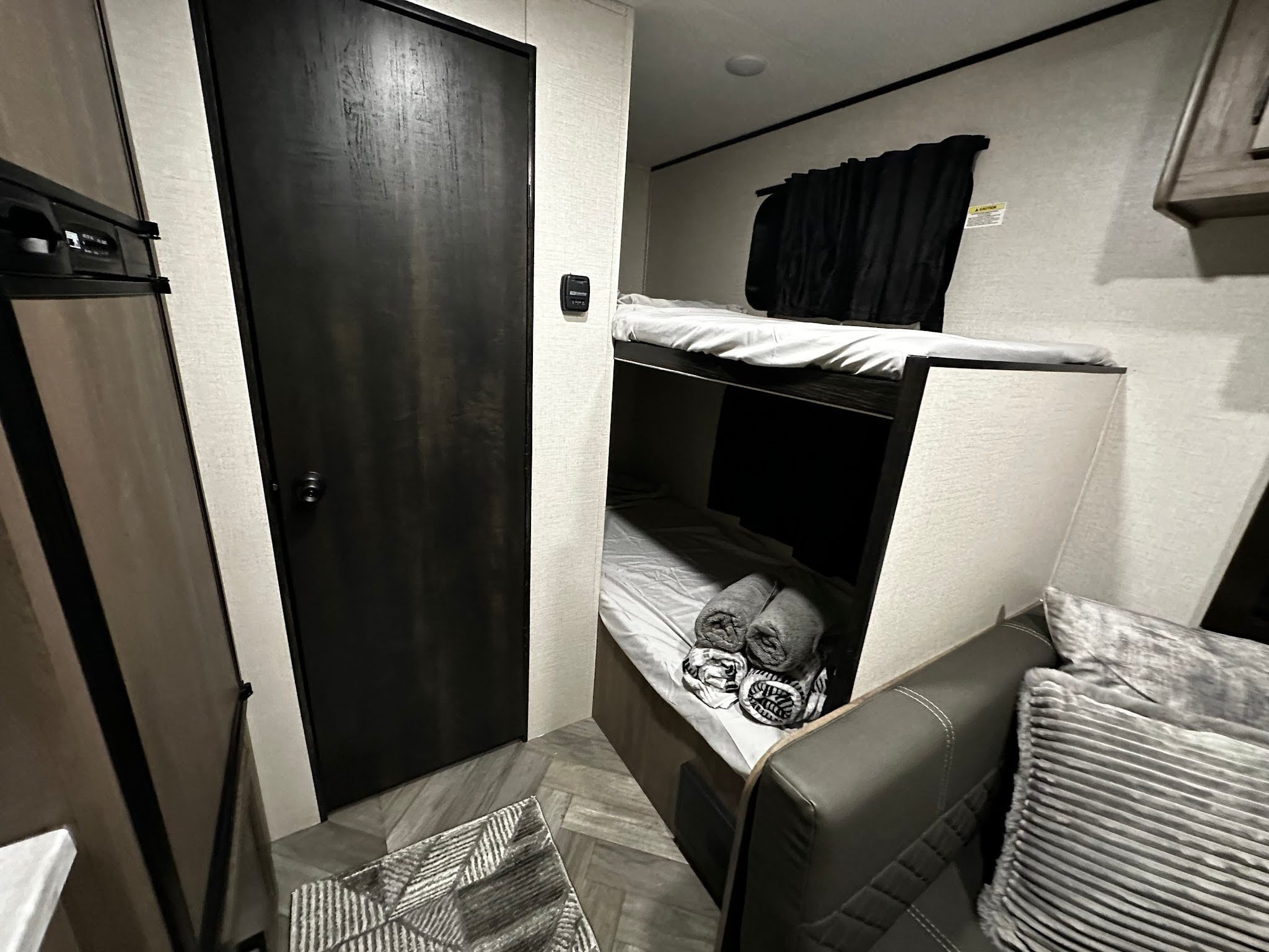 Cozy RV rental interior featuring bunk beds, a compact living area with couch, and a small fridge. Ideal for travel comfort.. Highland Ridge RV Oylmpia Sport 19BH 2021