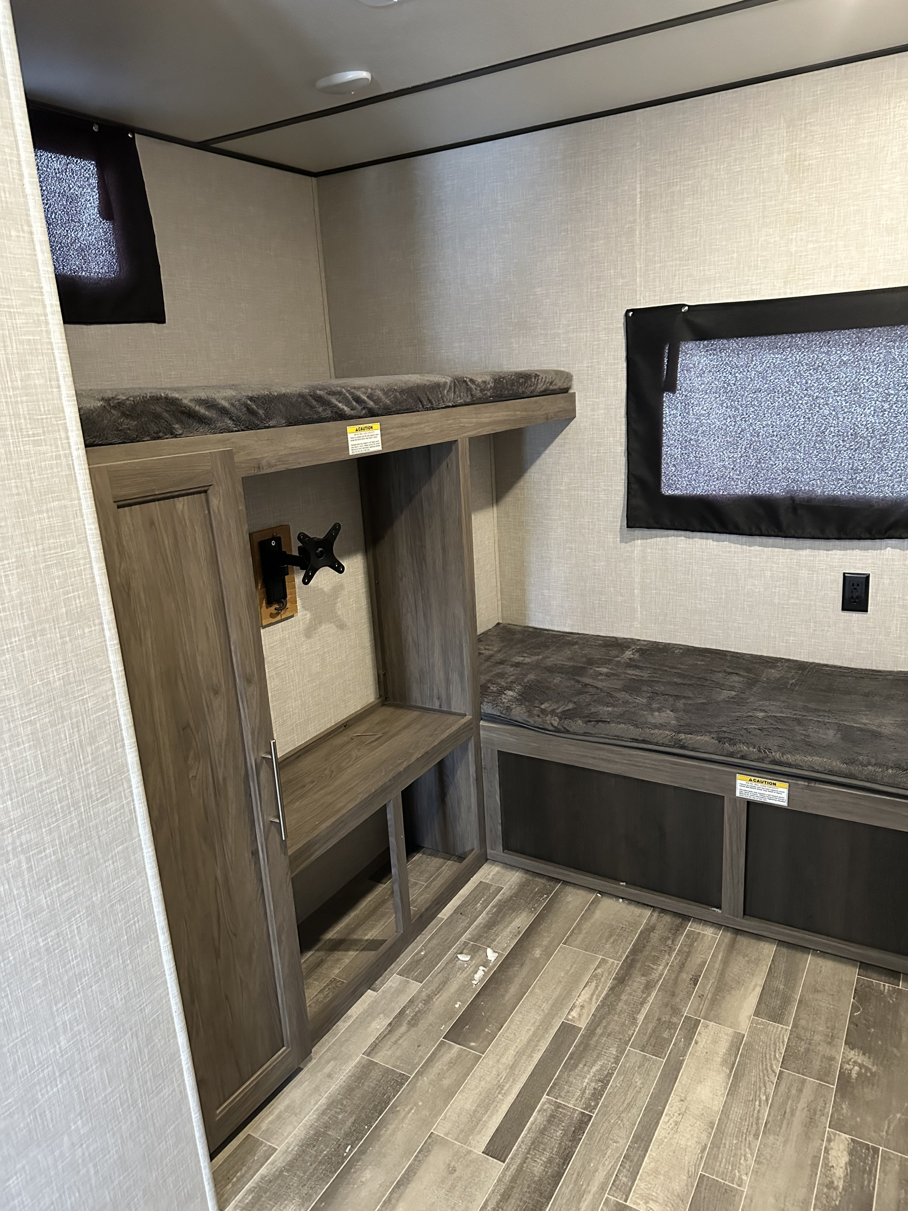 RV rental bunkhouse area: cozy bunk bed, bench seating with storage, TV mount, and window. Modern light interior walls & wood-look floor.. Crossroads RV Zinger 2021