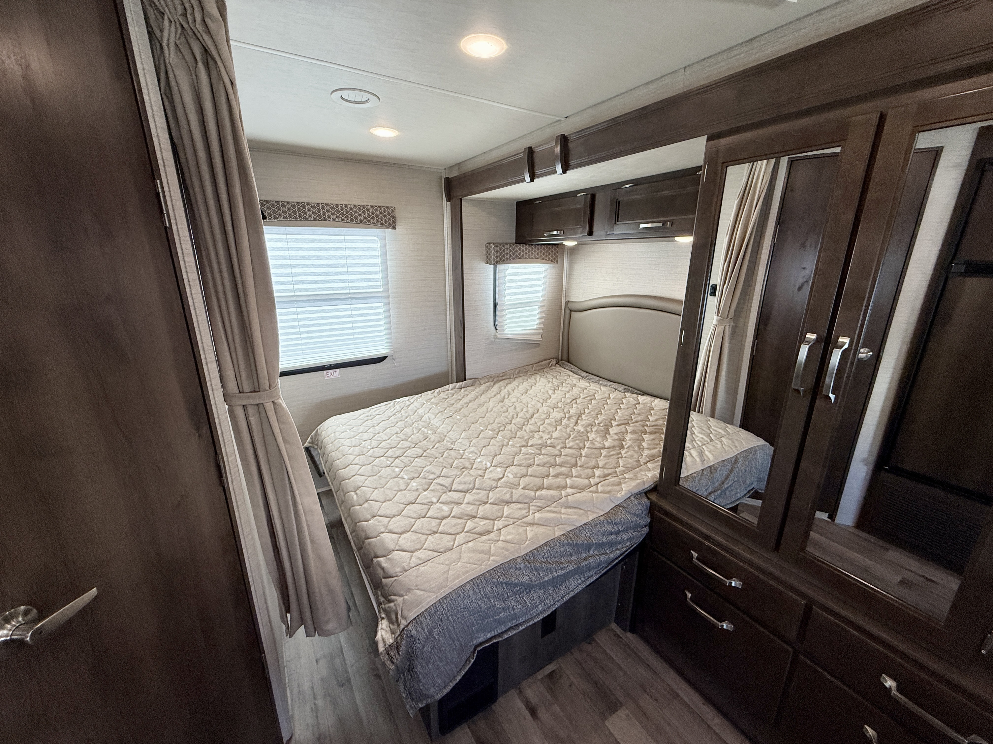 Cozy RV rental bedroom showcasing a quilted bed, windows with blinds, and a mirrored wardrobe for comfort.. Jayco Melbourne 2020