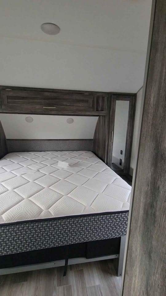 This RV rental bedroom features a clean mattress, overhead storage, and a mirrored wardrobe. Note ceiling discoloration.. Forest River Salem 2019