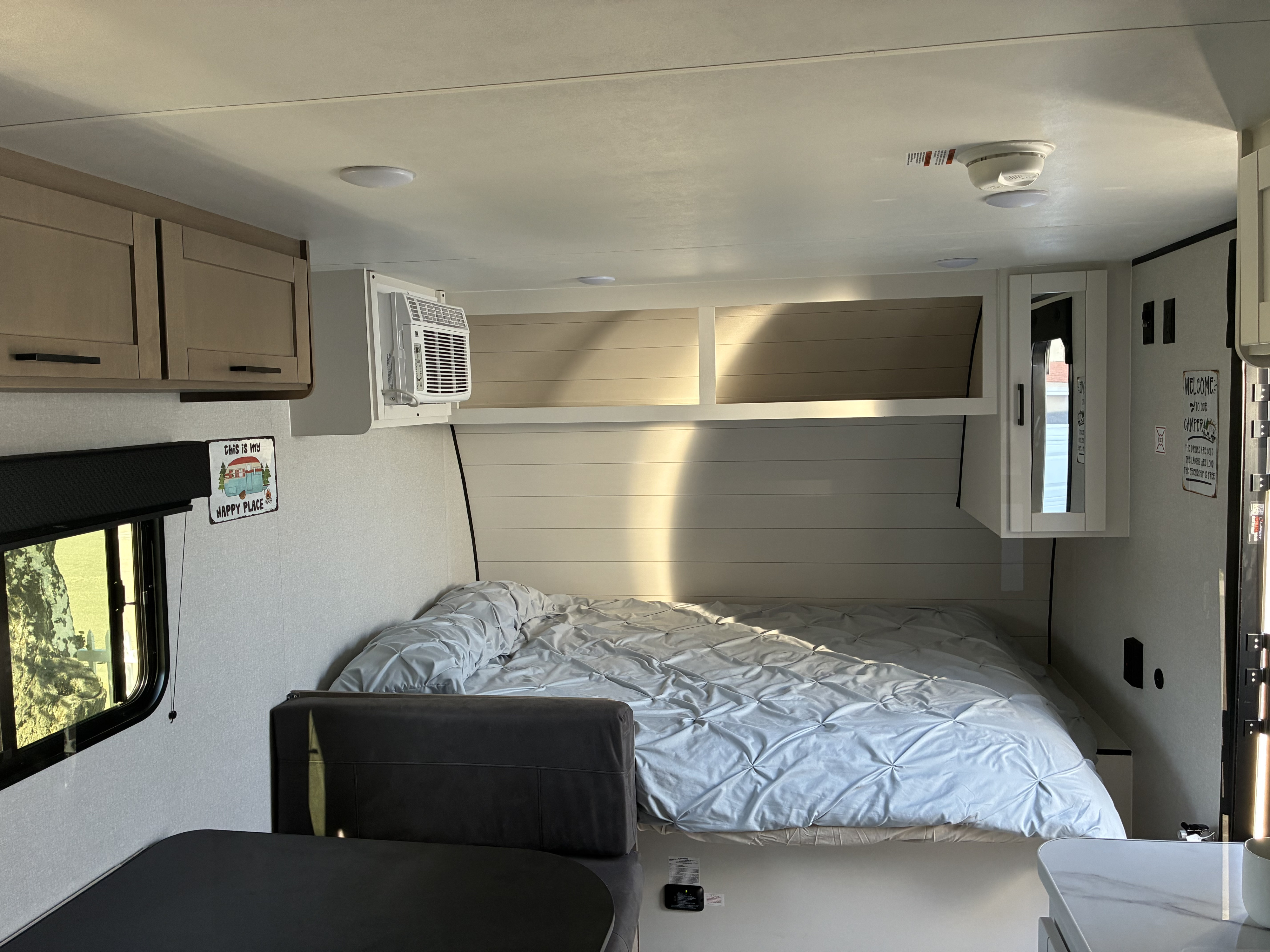 Bright rv rental interior: a cozy bed with blue comforter, small dinette, AC unit, and cheerful wall decor.. Jayco 1UJBC0AJ6F7750334 2026