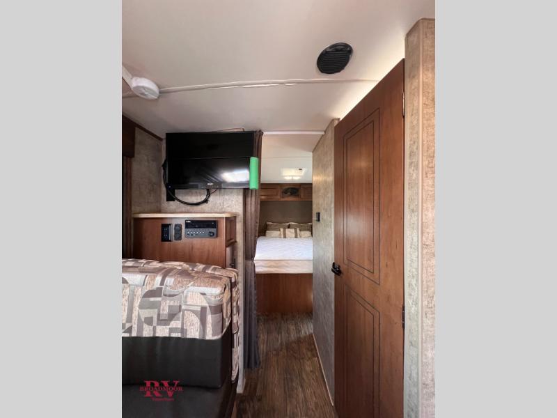 RV rental interior: a cozy bedroom view with a mounted TV, entertainment panel, and comfortable bed.. Outdoors RV Creekside 2017