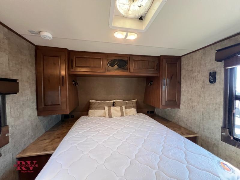 RV rental's cozy bedroom with a white mattress, wooden cabinets, side shelves, and a window for natural light.. Outdoors RV Creekside 2017