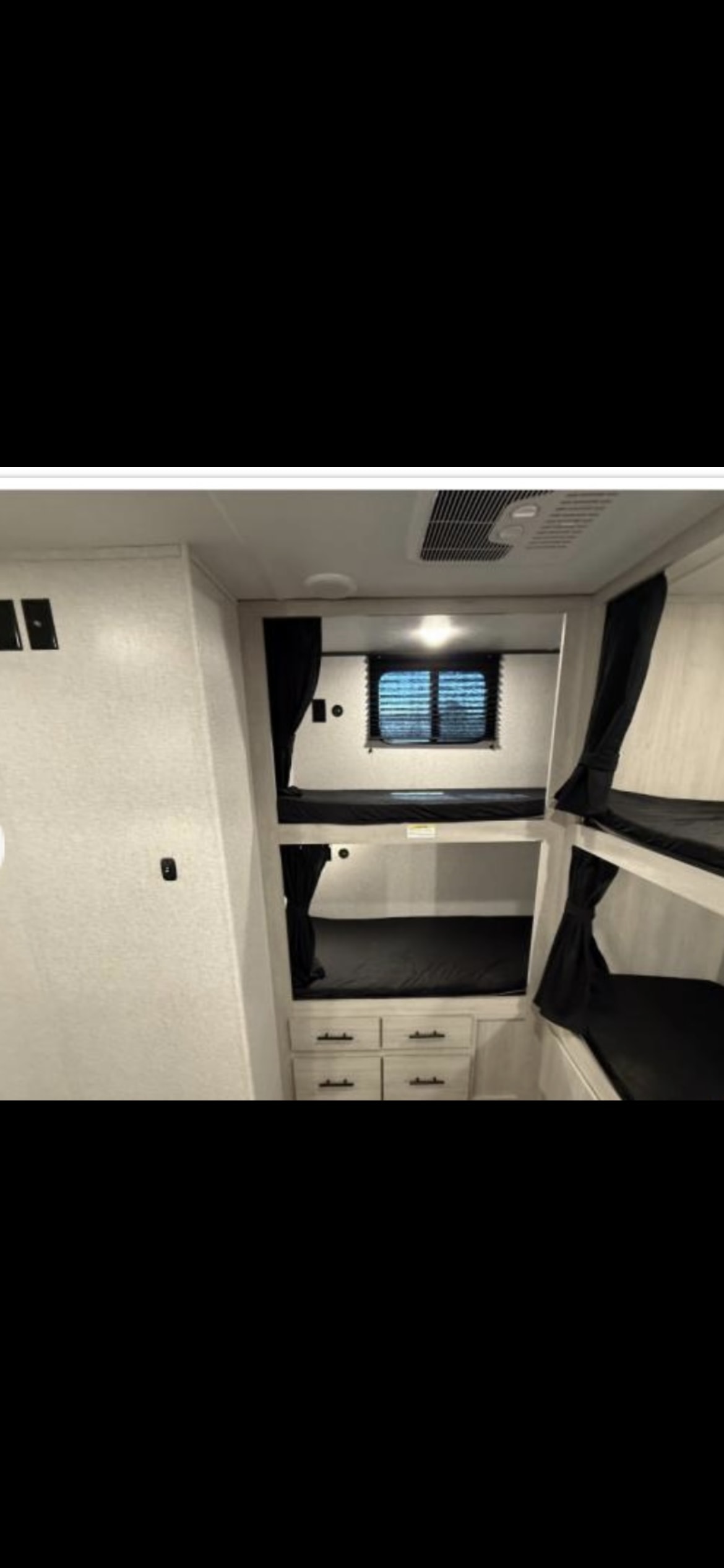RV rental bunkhouse featuring multiple black-curtained bunk beds, a window, and storage drawers, ideal for family trips.. Crossroads RV Zinger 2025