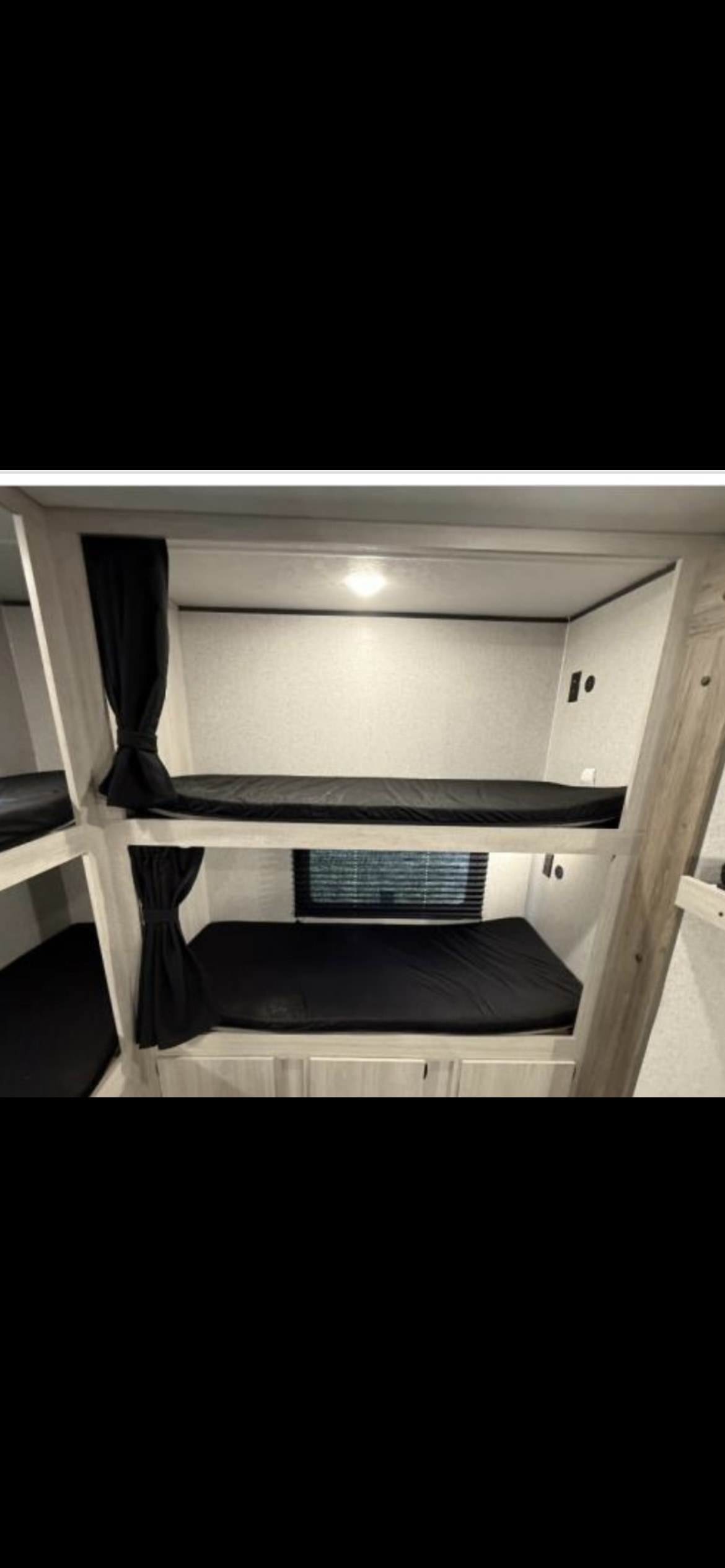 Inside an RV rental: cozy bunk beds with black mattresses and privacy curtains. Great for family adventures in a travel trailer.. Crossroads RV Zinger 2025