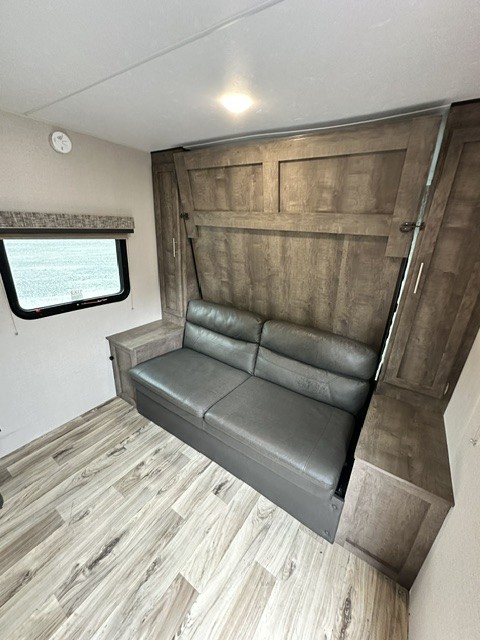 RV rental: Functional interior with a grey sofa/bed, wood paneling, overhead light, and window. Storage cabinets included.. KZ Escape 2019