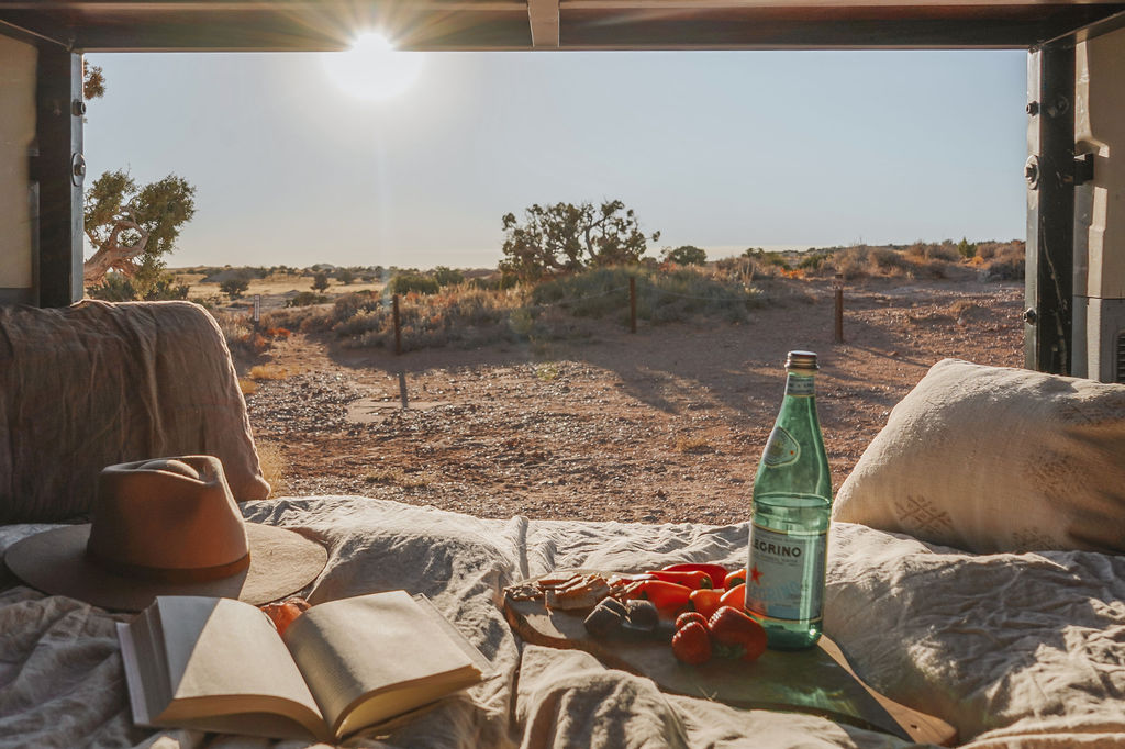 Relax in your cozy RV rental with a stunning desert view. Enjoy a book, snacks, and a refreshing drink for your outdoor escape.. Ford Transit Custom 2022