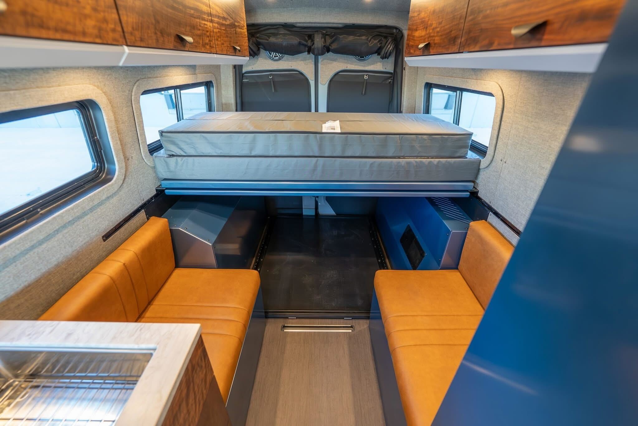 Explore this RV rental's spacious camper van interior featuring an elevated bed, comfy benches, and a convenient kitchen.. Mercedes-Benz Sprinter 2026