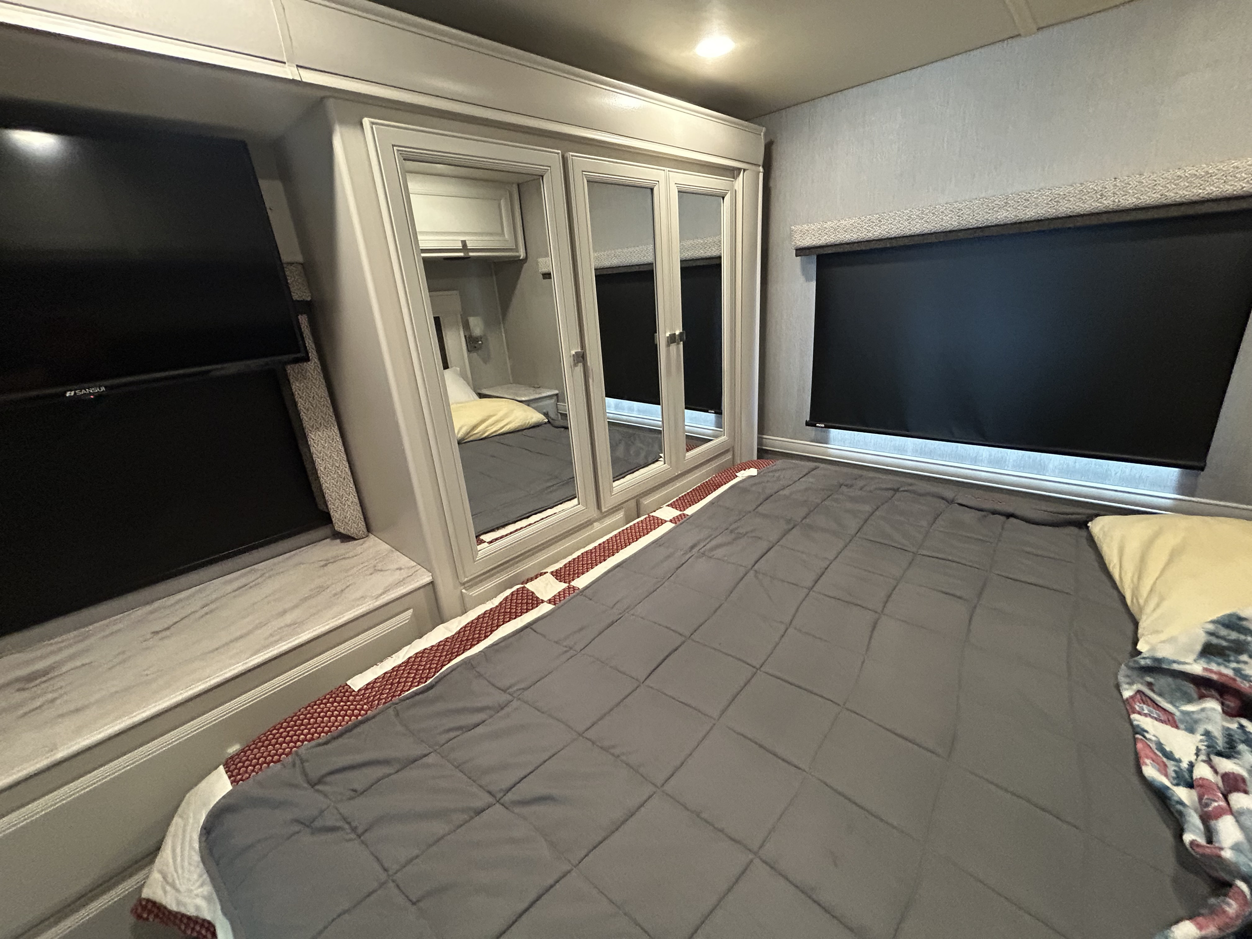 Modern RV rental bedroom with cozy bed, built-in TV, and mirrored closet for comfortable travel.. Holiday Rambler Admiral 2021