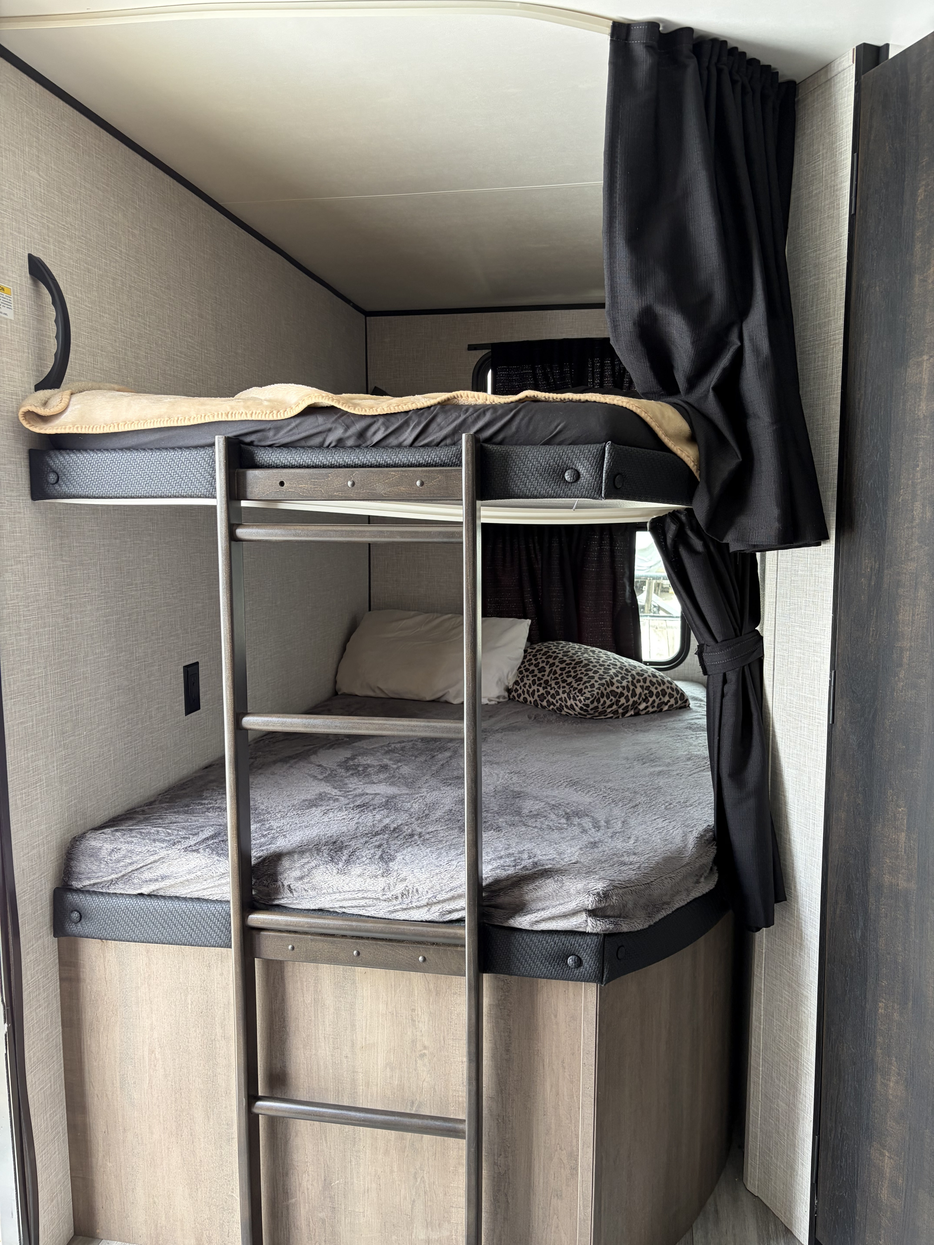Cozy bunk beds in an RV rental, featuring a ladder, comfortable bedding, and privacy curtains. Ideal for family travel.. Jayco Jay Flight 2024