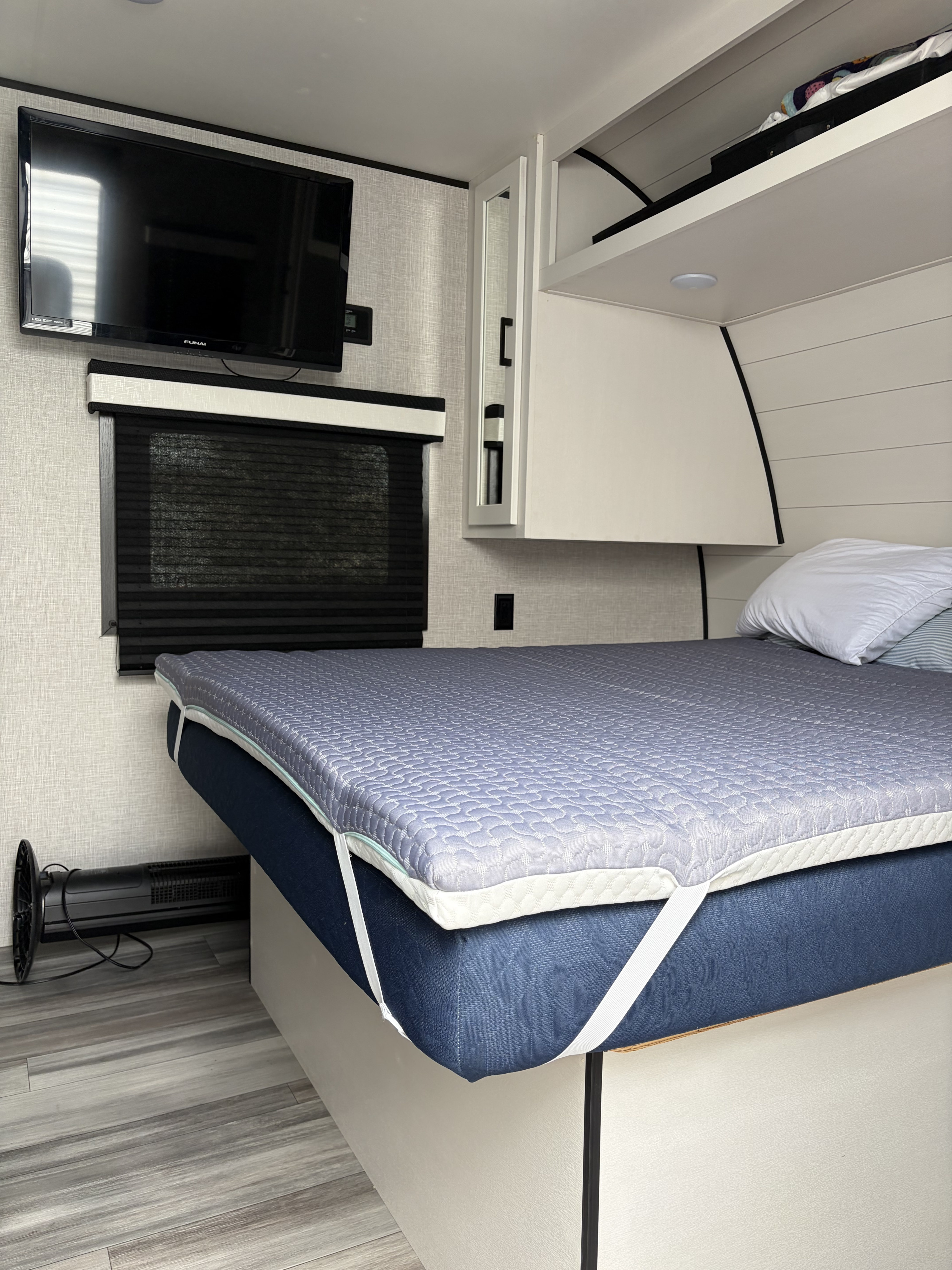 Modern rv rental bedroom with a comfy bed, quilted topper, wall-mounted TV, window blind, and storage units.. Jayco Jay Flight 2024