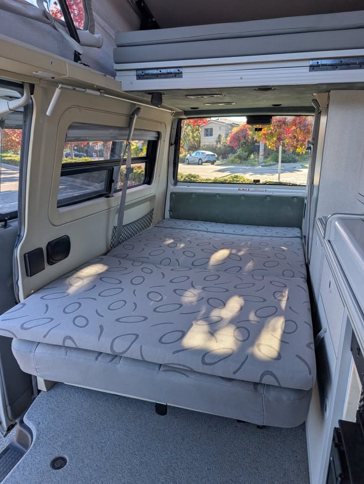 Spacious RV rental interior featuring a comfortable fold-down bed, an upper bunk, and large windows.. Eurovan Camper Eurovan Camper Class B 2001
