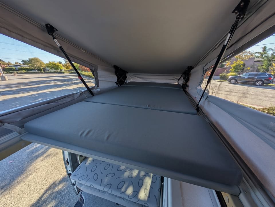 Comfortable pop-top camper **rv rental** interior showing the elevated bed platform and open roof structure.. Eurovan Camper Eurovan Camper Class B 2001