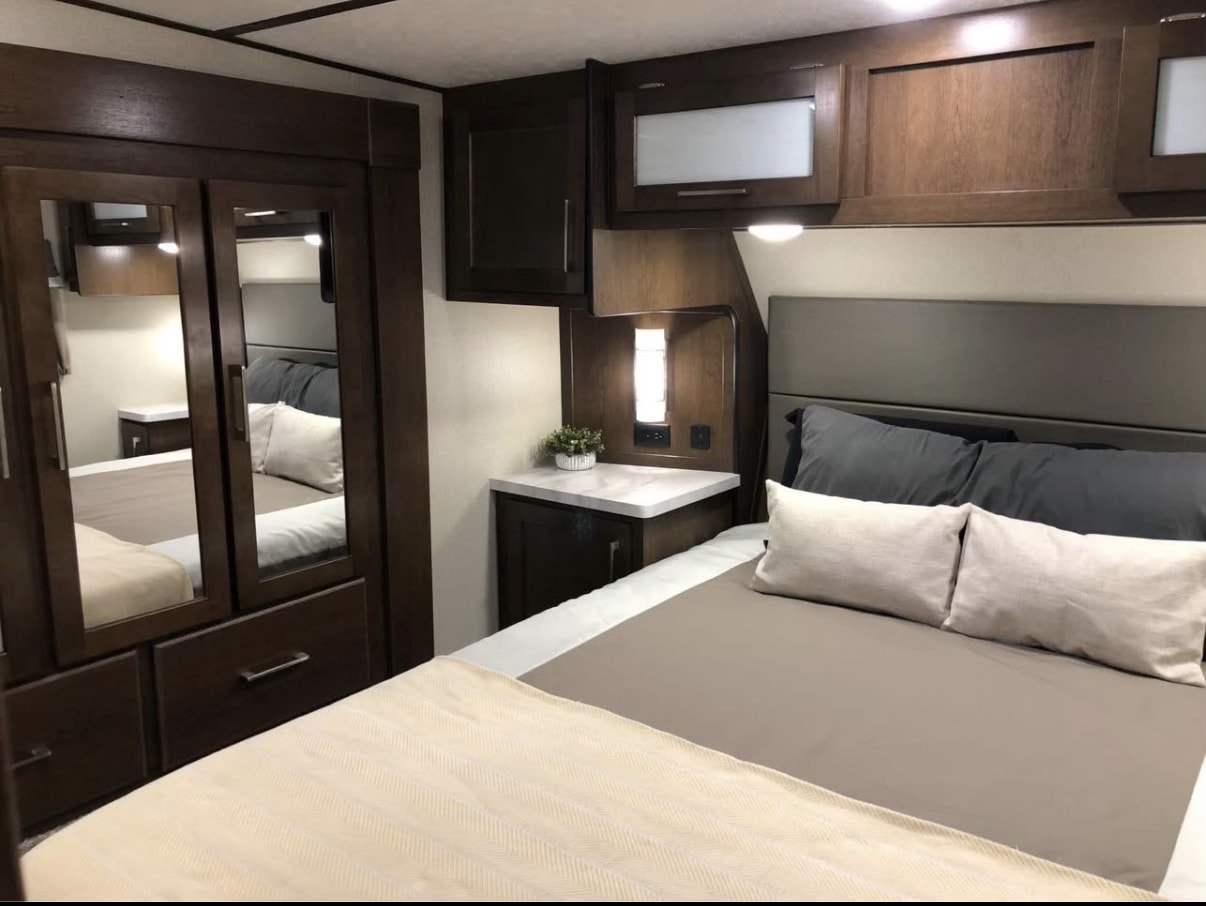 Enjoy a comfortable sleep in this modern RV rental bedroom, complete with a cozy bed, sleek cabinetry, and ambient lighting.. Crusader Lite 2020