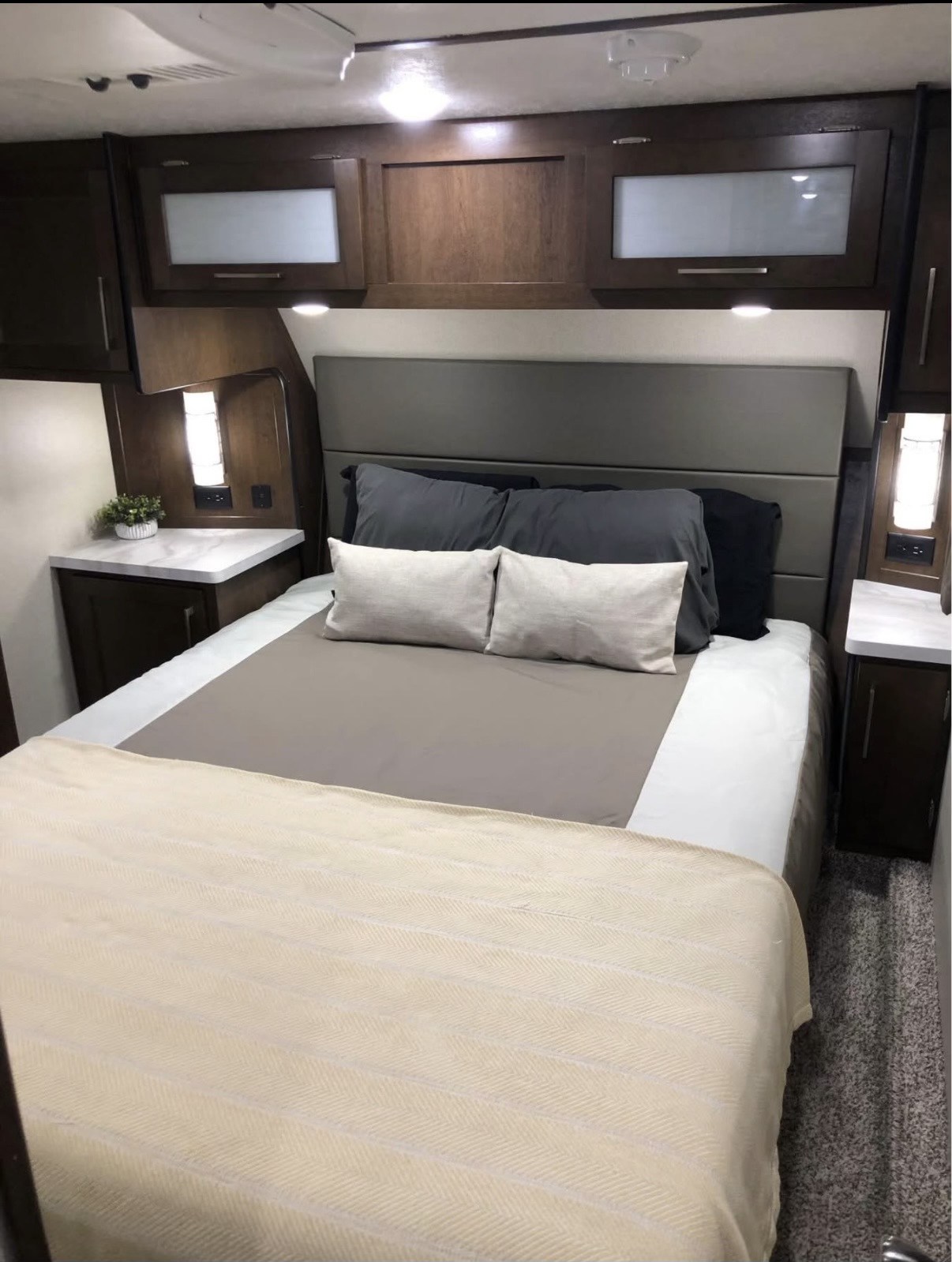 Cozy RV rental bedroom with a queen bed, nightstands, and overhead storage. Ideal for comfortable travel accommodations.. Crusader Lite 2020