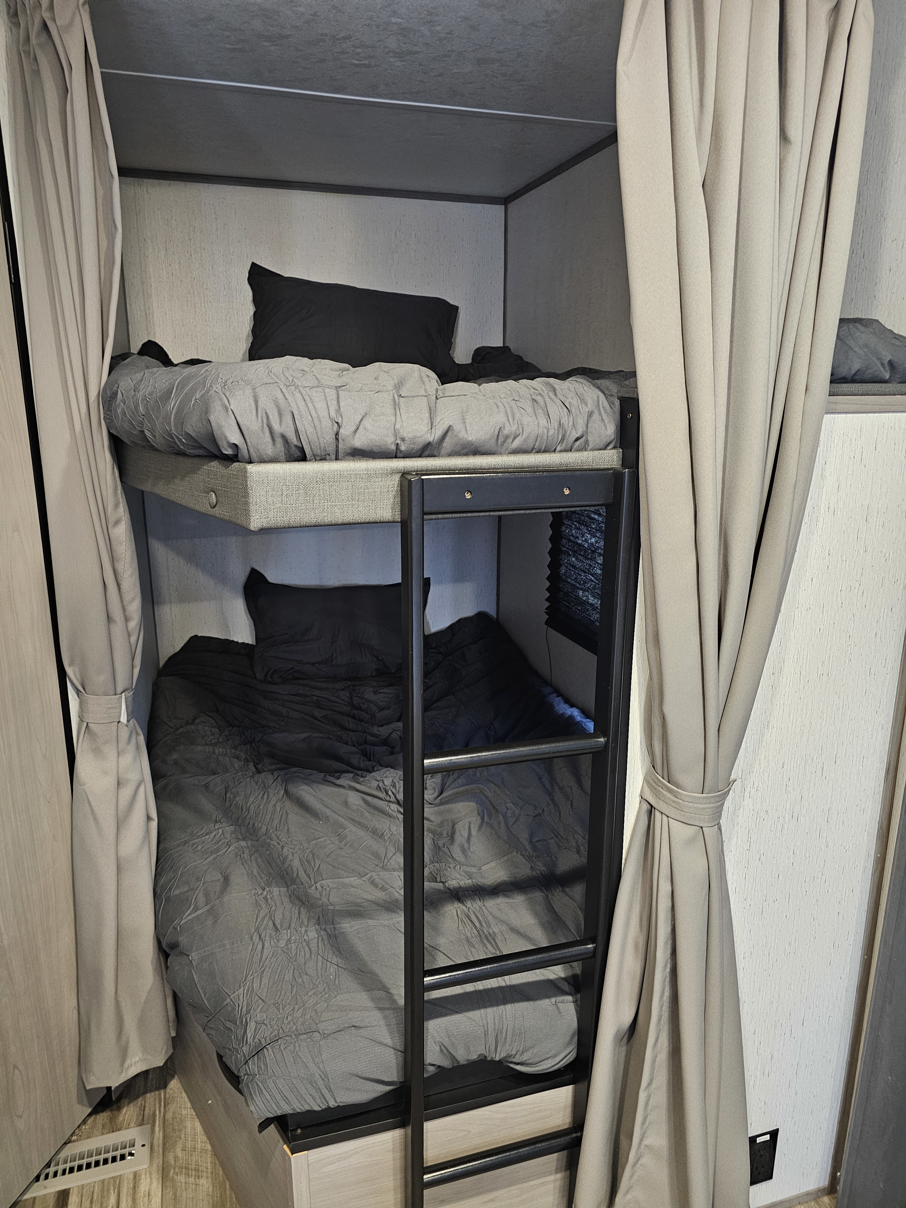 RV rental bunk beds: comfortable, compact sleeping area with grey bedding, ladder, and privacy curtains.. Dutchmen Coleman Lantern LT 2022