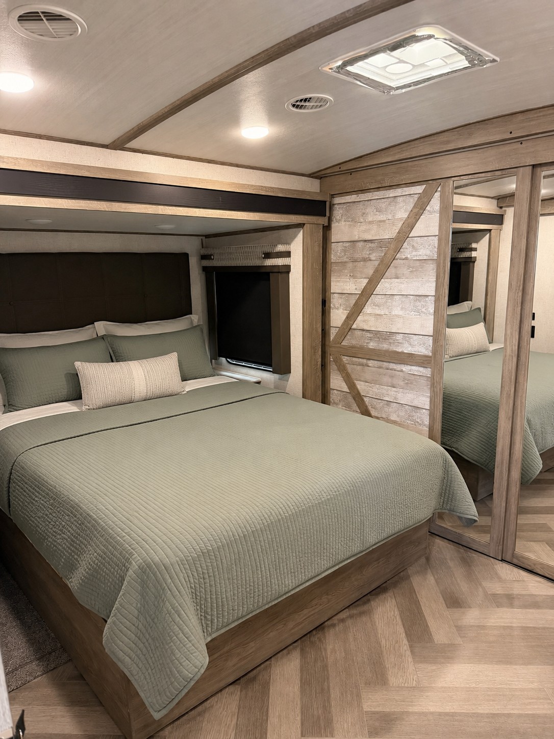 Cozy RV rental bedroom features a queen bed, green bedding, wood-paneled ceiling, and mirrored wardrobe for a comfortable stay.. Forest River Salem Hemisphere 2020
