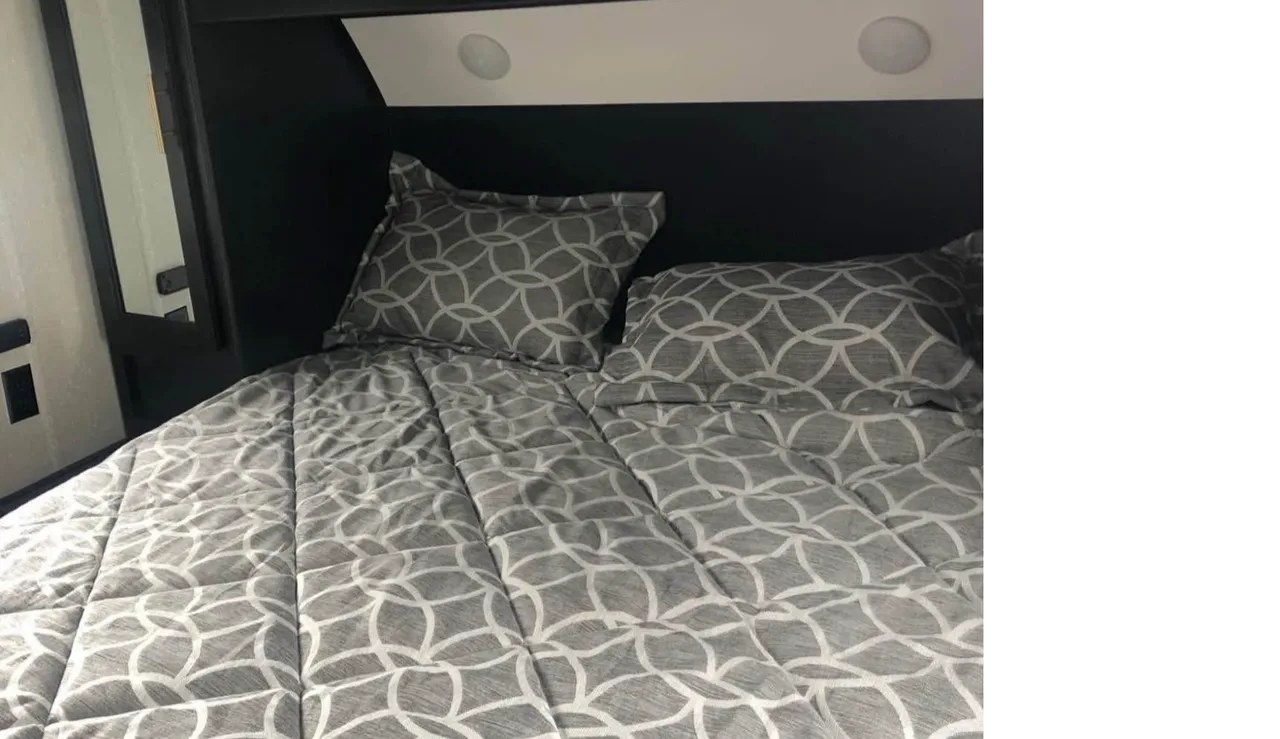 Cozy gray geometric bedding and pillows in an RV rental bedroom. This compact sleeping area is ready for your adventure.. Forest River Cherokee 2022