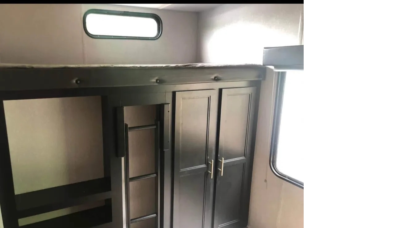 View inside an RV rental showing a dark bunk bed, ladder, wardrobe, and windows. Great for family trips.. Forest River Cherokee 2022