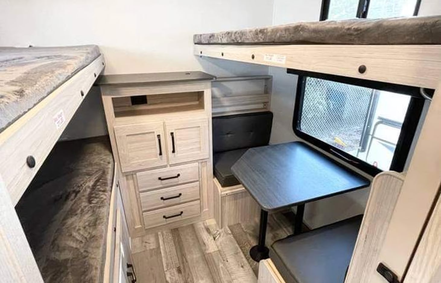 RV rental interior: light-toned bunk beds, dinette, and storage cabinets. Perfect compact living space for families.. Heartland RVs Sundance Ultra Lite 2022