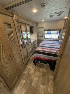 Cozy RV rental bedroom showcasing a bed, wardrobe, dresser, and modern flooring. Ideal for comfortable travel and storage space.. Forest River Coachmen Mirada 2020