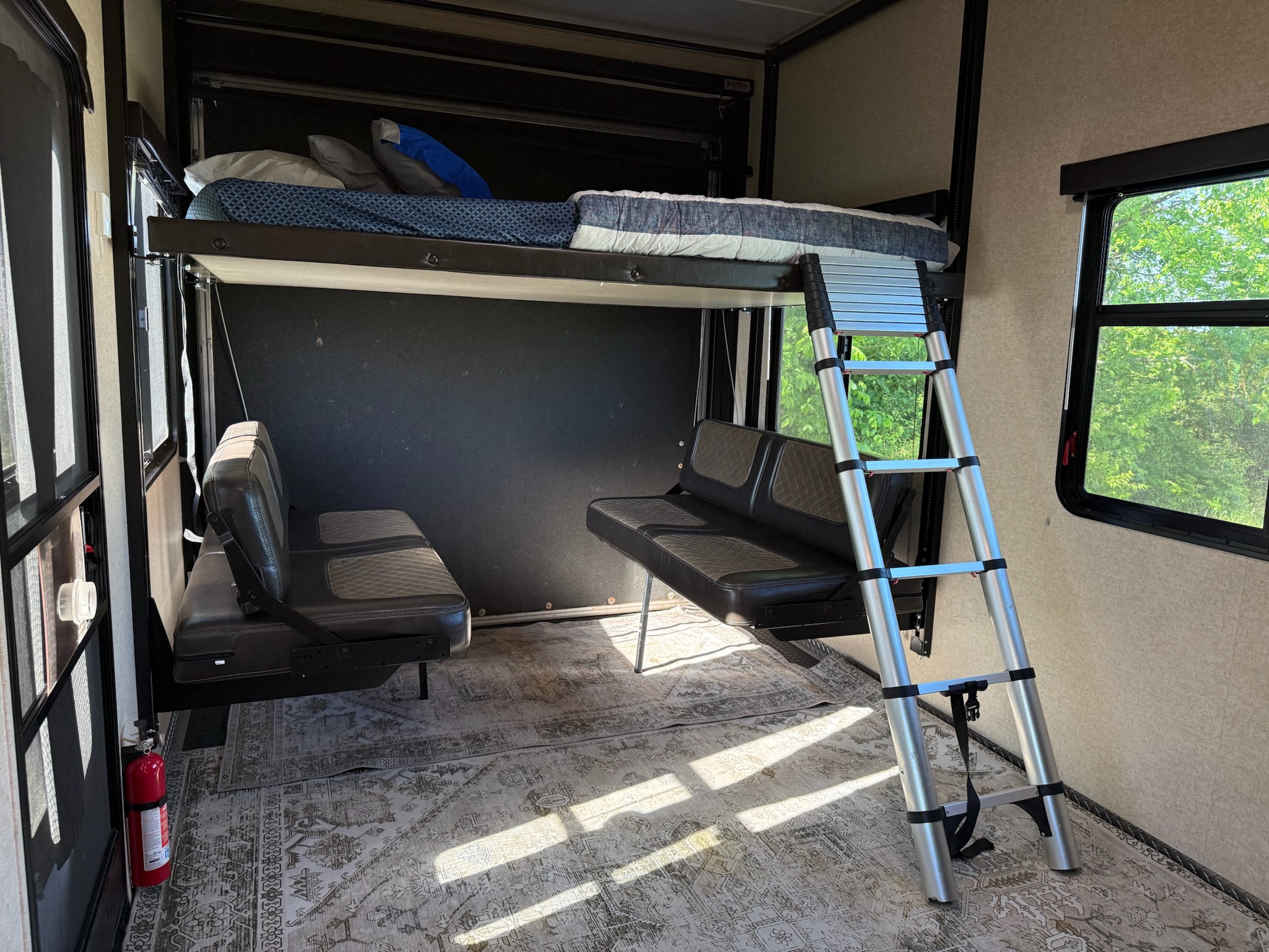 RV rental interior: bunk bed with ladder, two fold-down seats, and a patterned rug for flexible living.. Heartland RVs Torque Toy Hauler 2017