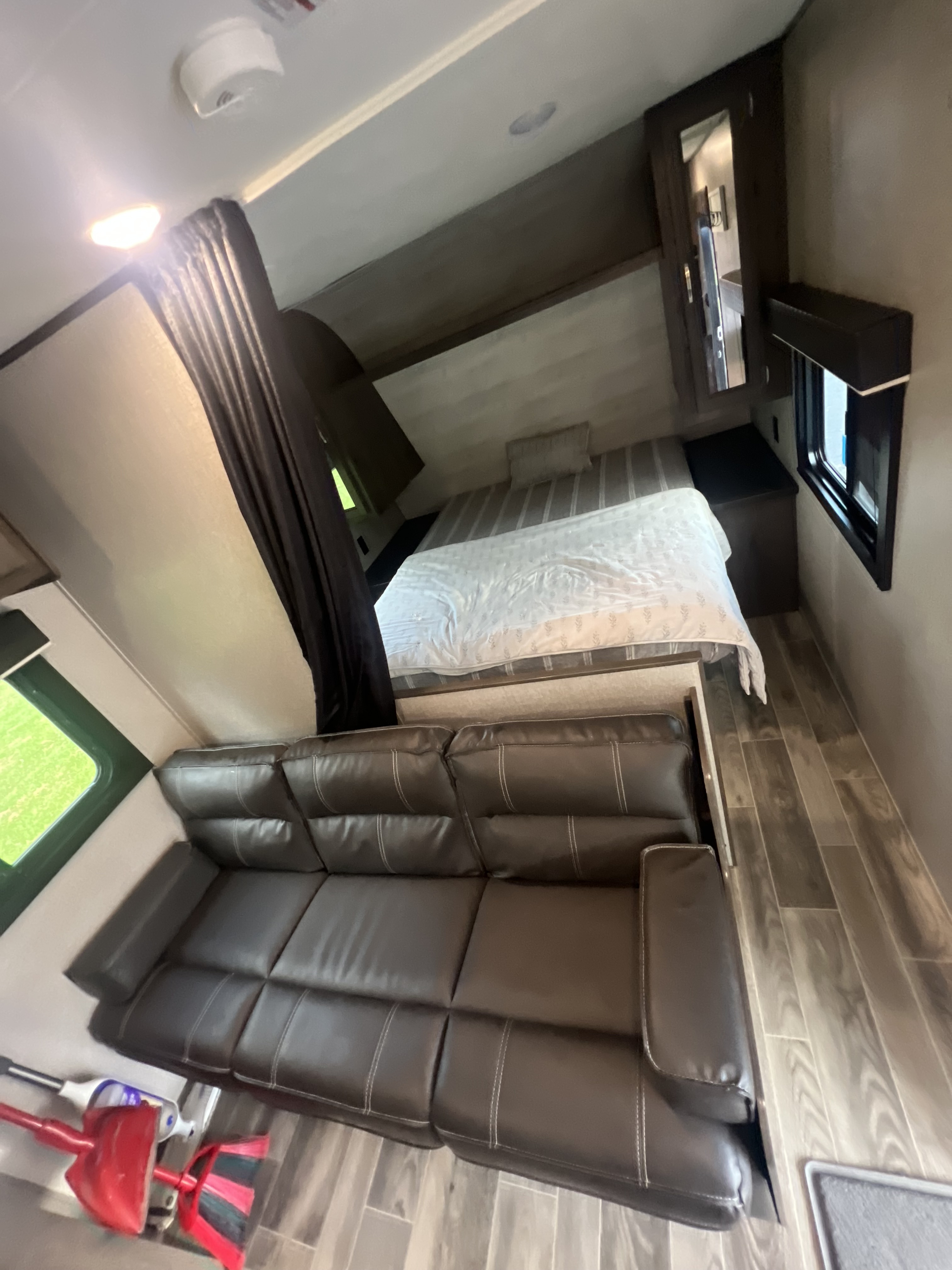 RV rental interior: features a cozy bed with white linens, a dark leather sofa, and wood-look flooring for travel.. Jayco Jay Flight SLX 2021