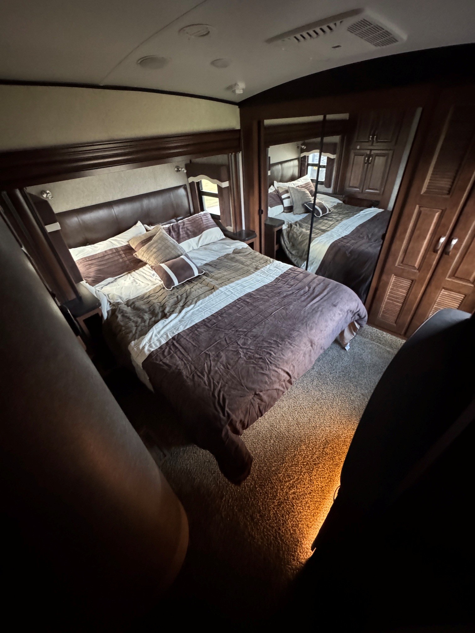Cozy RV rental bedroom with a comfortable bed, brown and white bedding, a headboard, and mirrored closet.. Jayco North Point 2017