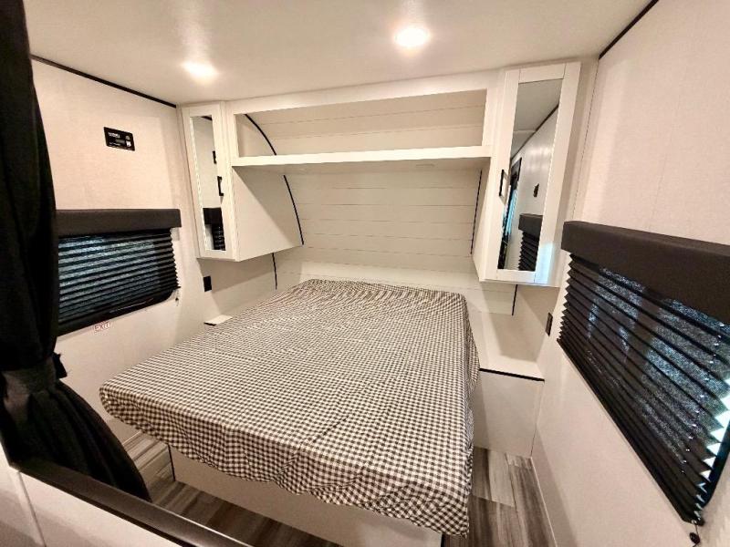 Modern RV rental bedroom with a checkered bed, built-in overhead cabinets, and windows with blinds. Comfortable travel space.. Jayco Flight SLX 260BH 2026