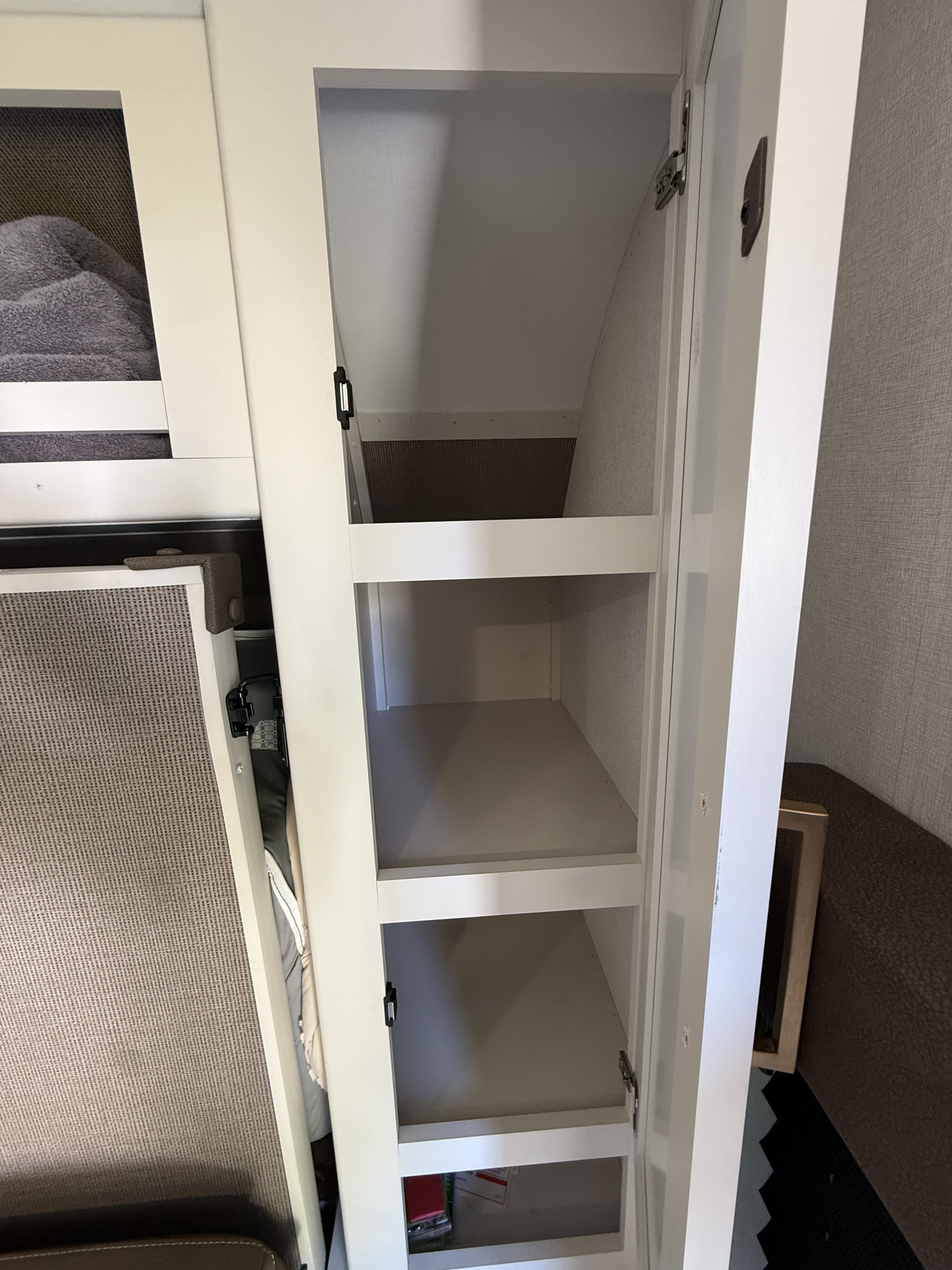 Open storage cabinet inside an RV rental, featuring several empty shelves. Ideal for organizing essentials during your trip.. Grand Design Transcend One 2026
