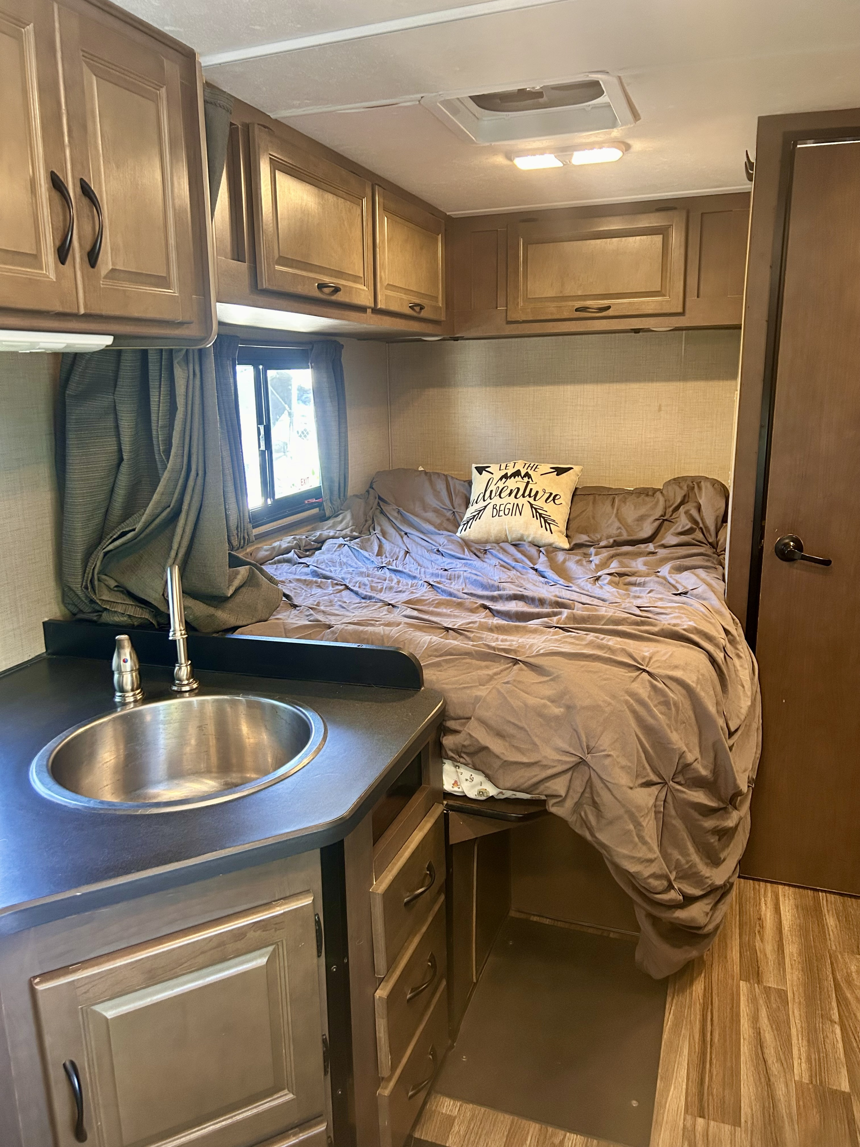 RV rental interior features a snug bedroom with a comfy bed, overhead cabinets, and a compact sink area for easy travel.. Thor Majestic 2018