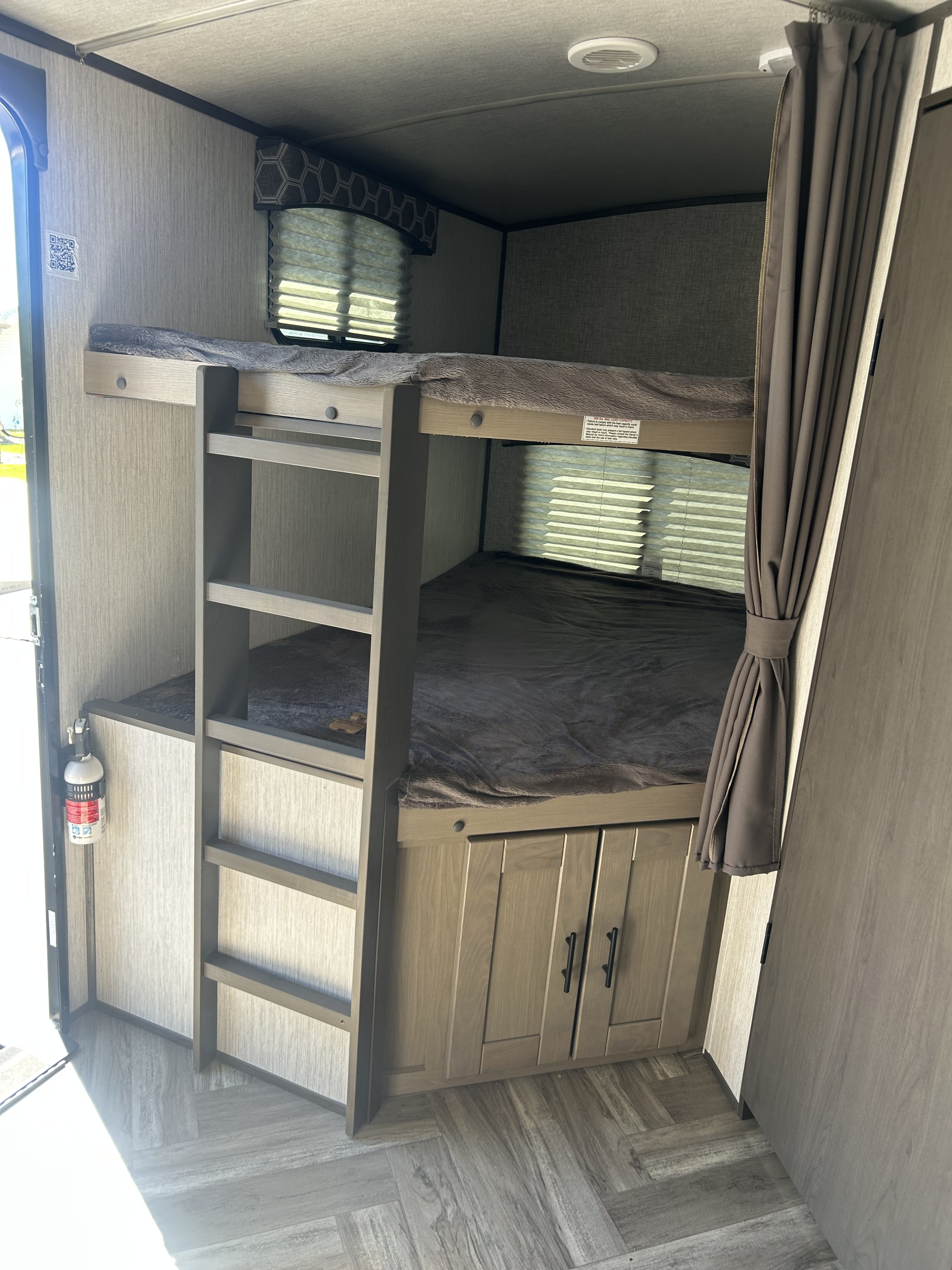 Cozy RV rental interior featuring comfortable bunk beds with a ladder, storage cabinets, and a fire extinguisher.. Cruiser RV Shadow Cruiser 2022