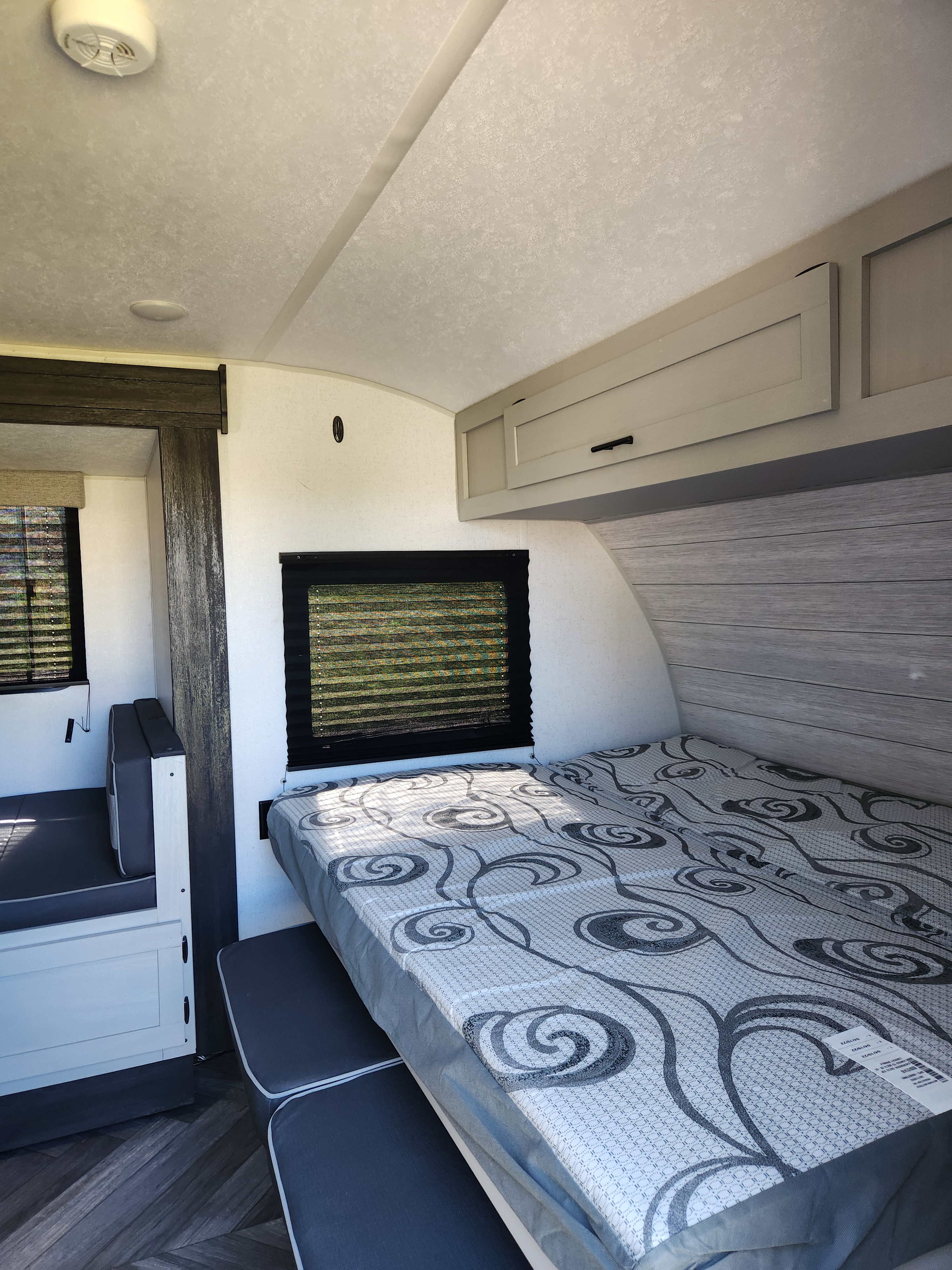 Inside this RV rental: a neat bed with patterned mattress, dinette, and sleek overhead cabinets. Ready for your trip!. Forest River Wildwood FSX Plantium 2022